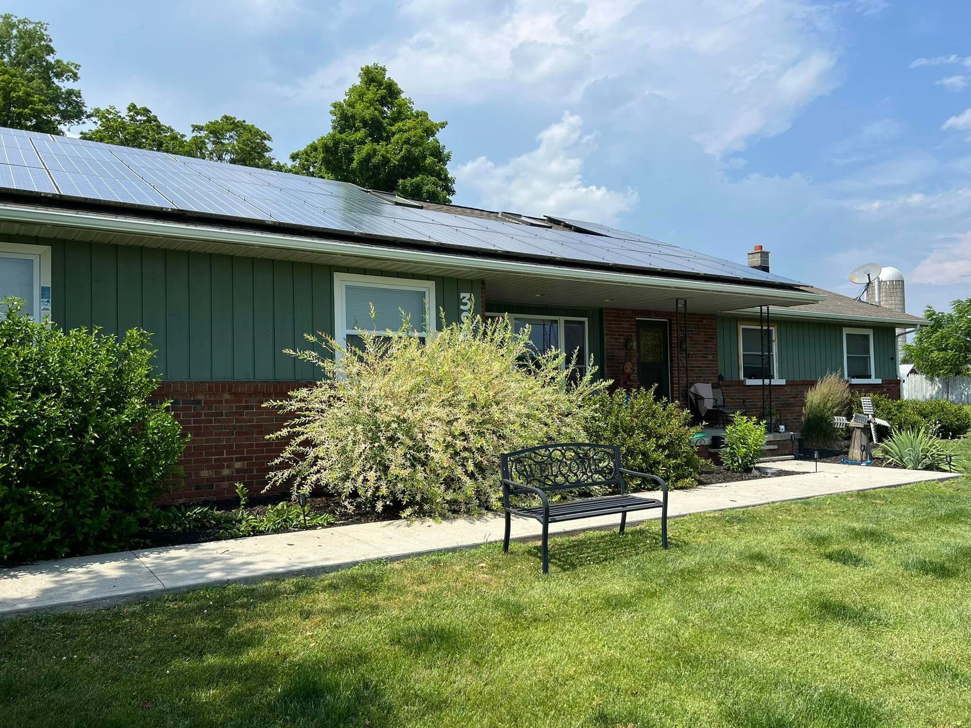 A house with green siding and a bench in front of it