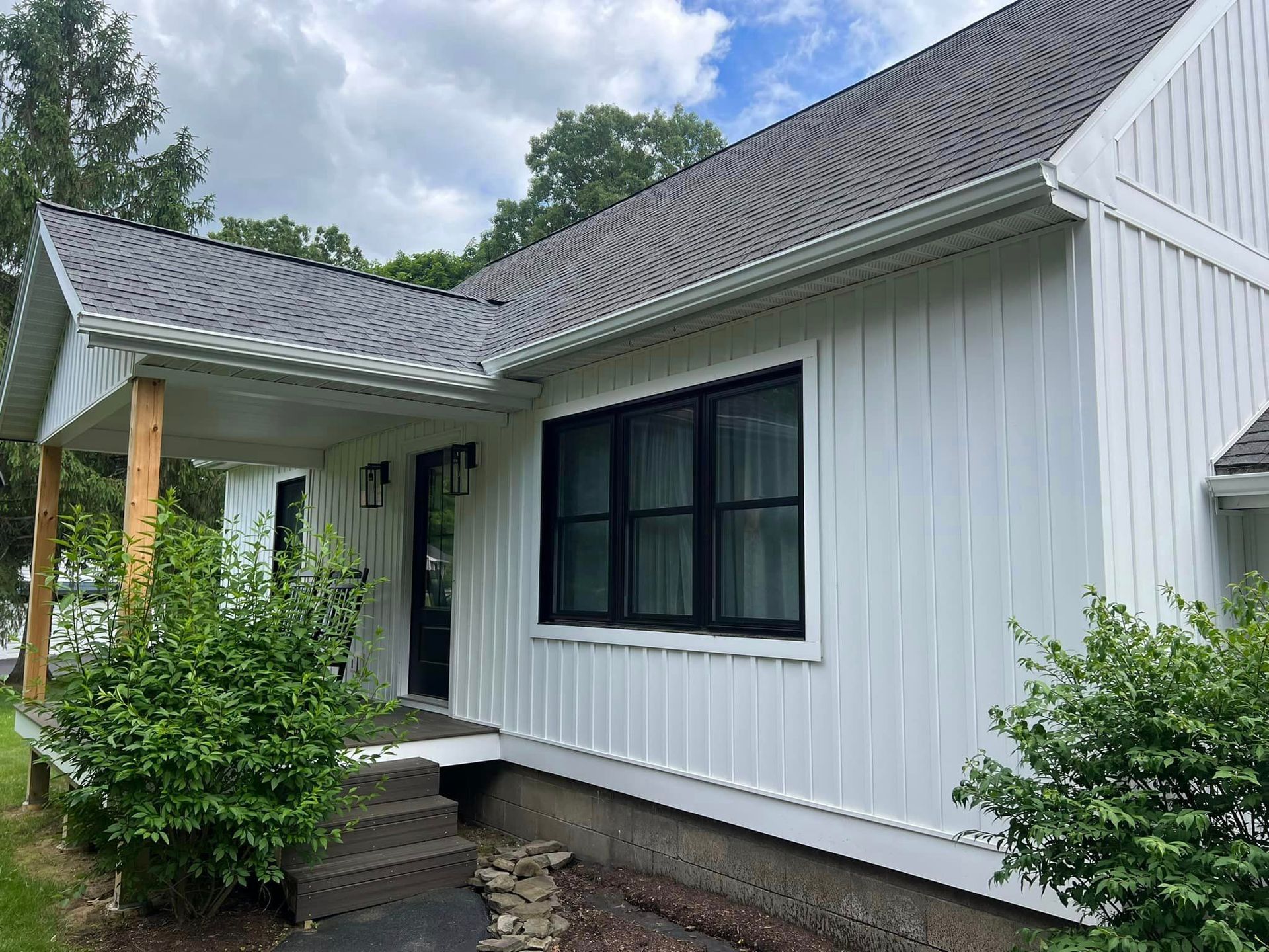 A white house with black windows and a gray roof