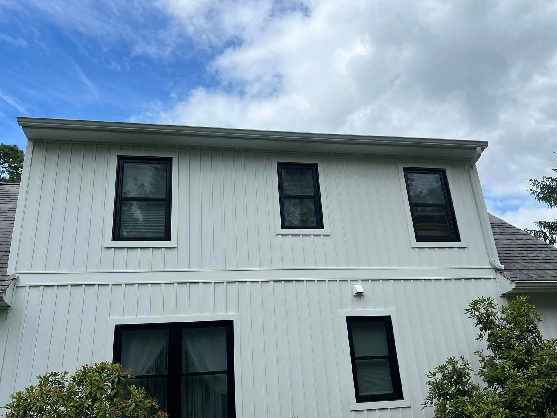 A white house with black windows and a blue sky in the background
