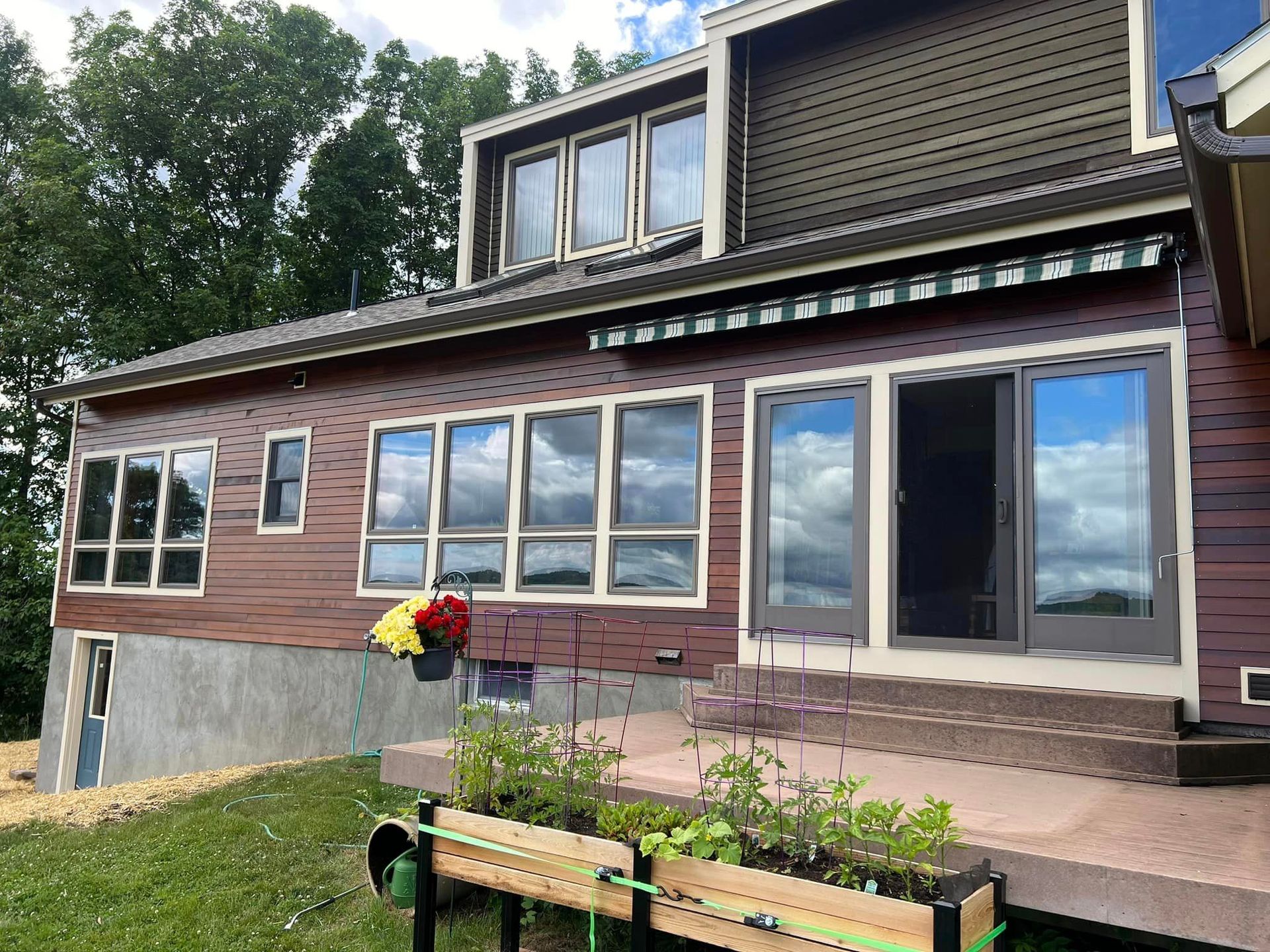 A large house with a lot of windows is sitting on top of a lush green hillside
