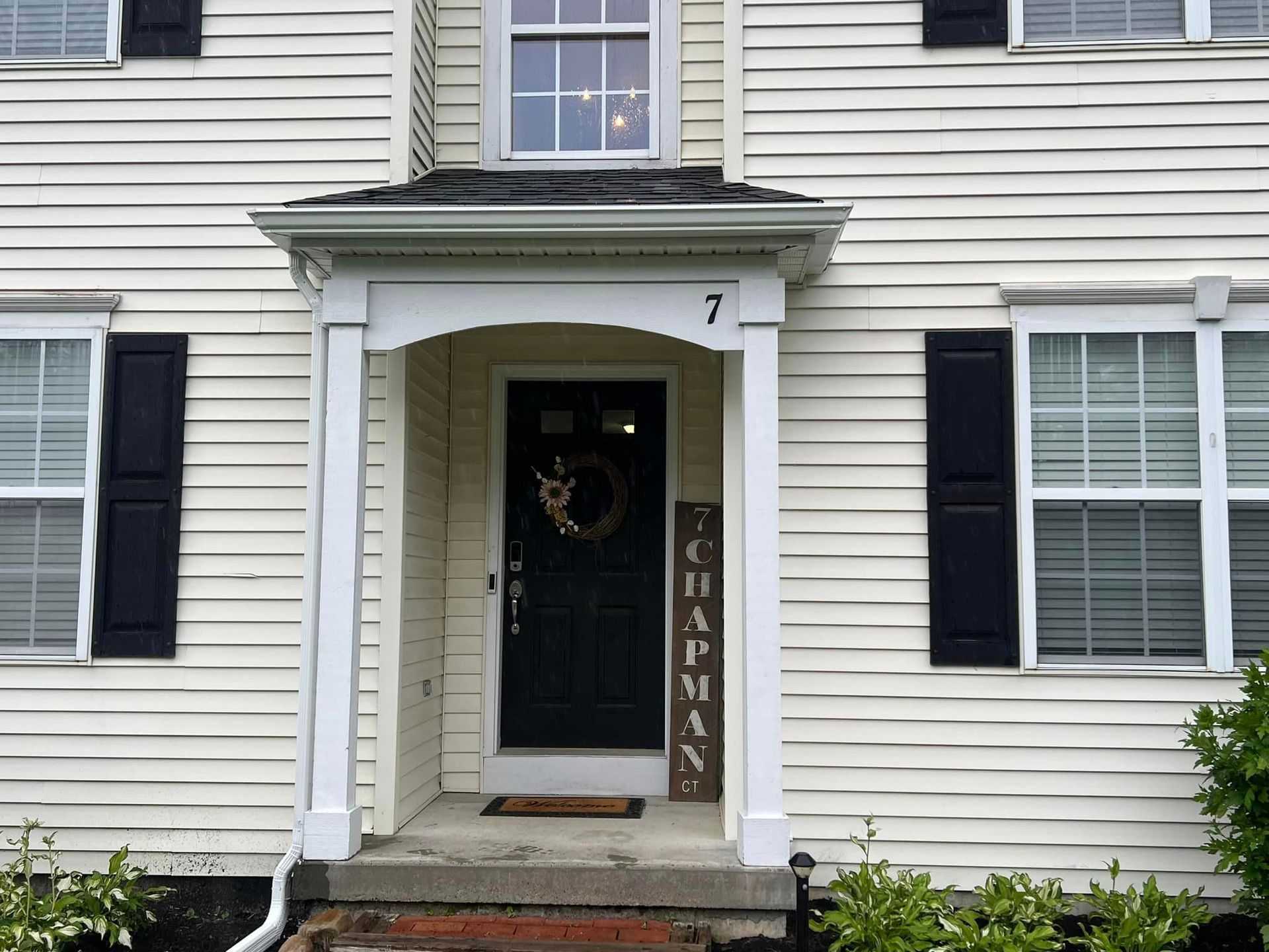 A white house with black shutters and a sign that says Chapman