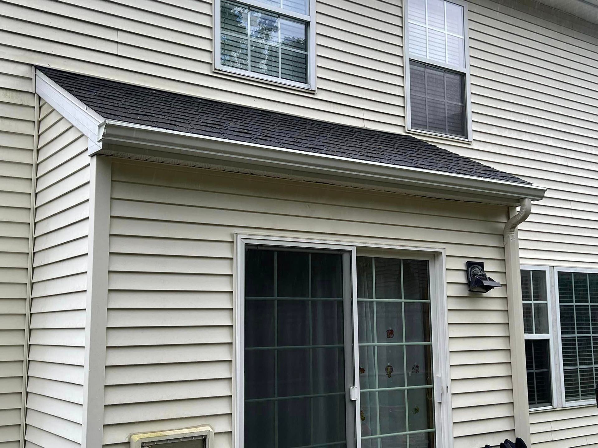 A white house with a sliding glass door and a black roof