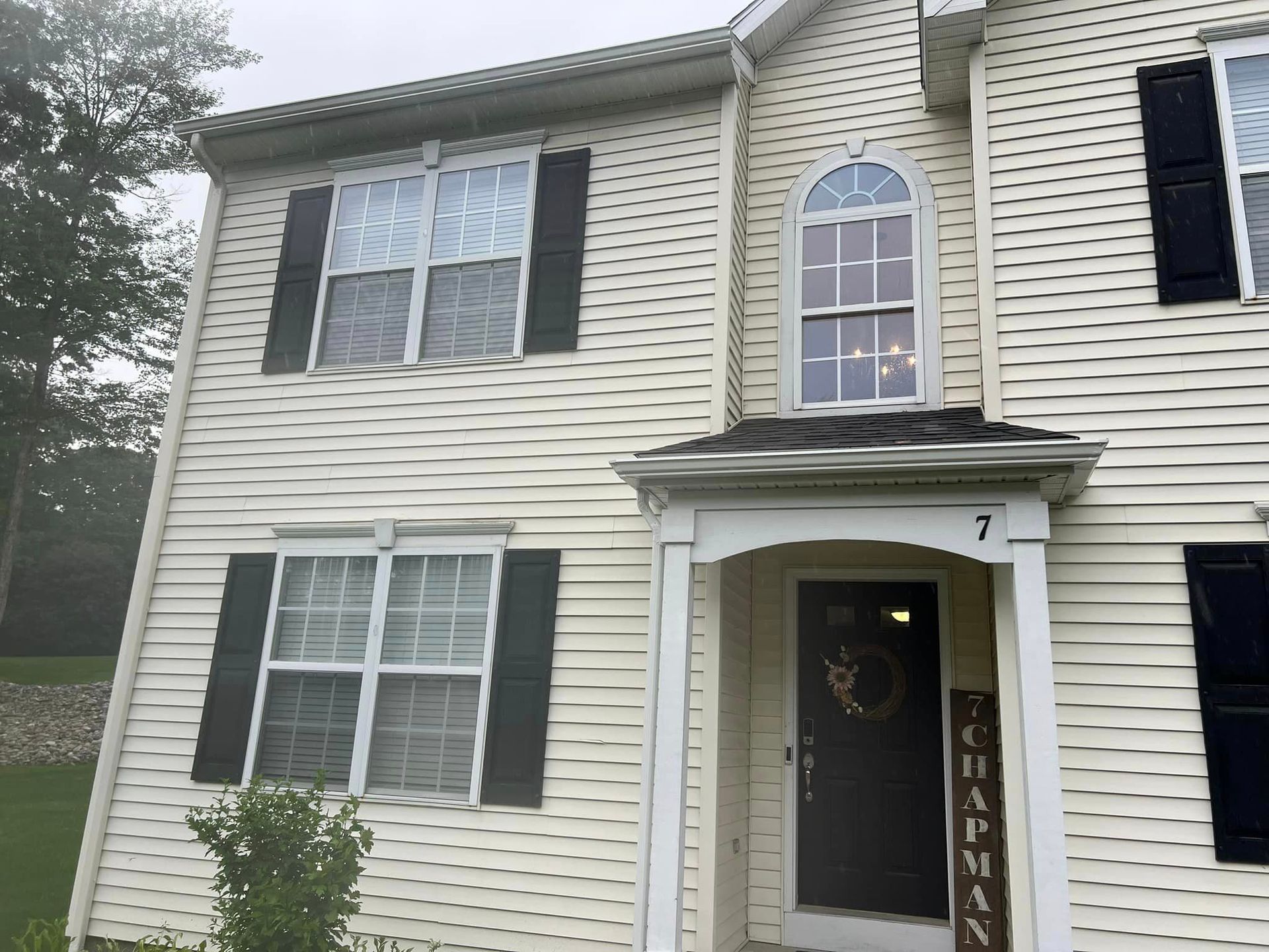 The front of a white house with black shutters and a porch