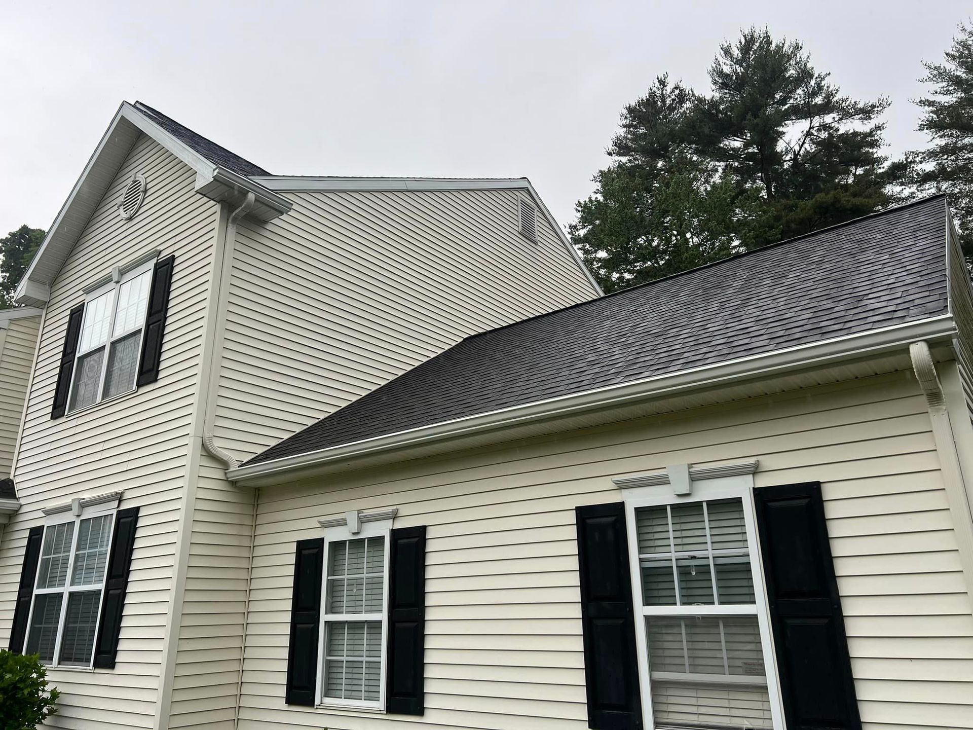 A white house with black shutters and a gray roof