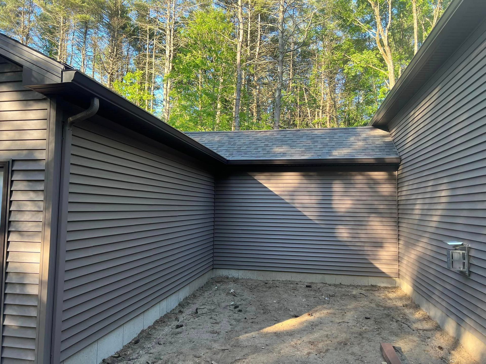 A house with a garage door is surrounded by trees