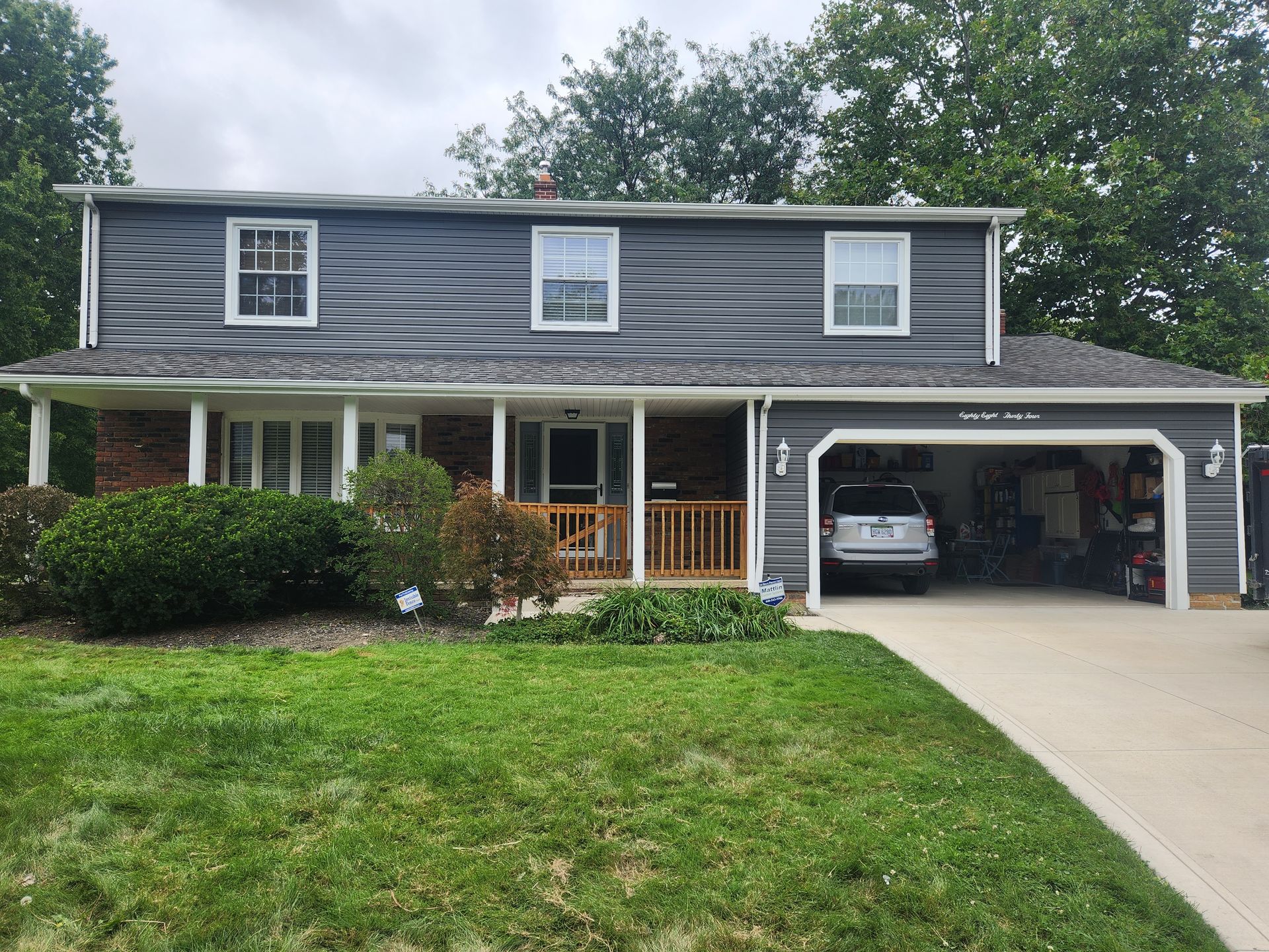 Two-story house with gray siding and white trim, a garage, and green lawn.