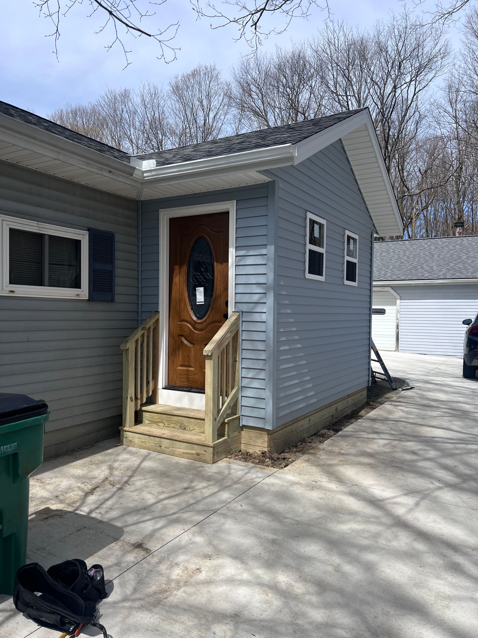 A light blue house with a wooden door and ramp leading to the entrance.