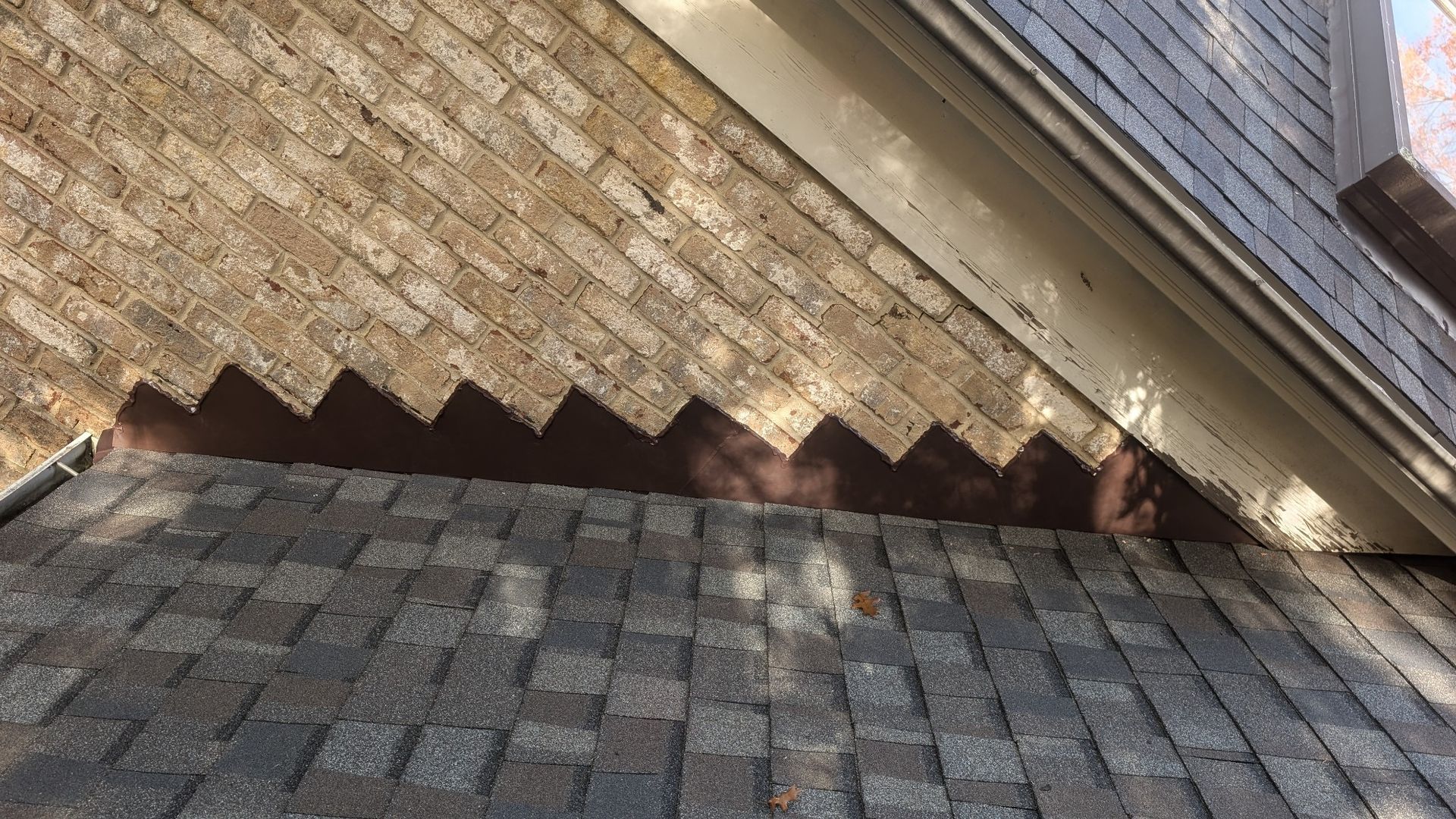Brown shingled roof with a dark brown, sawtooth-edged metal flashing at the edge.