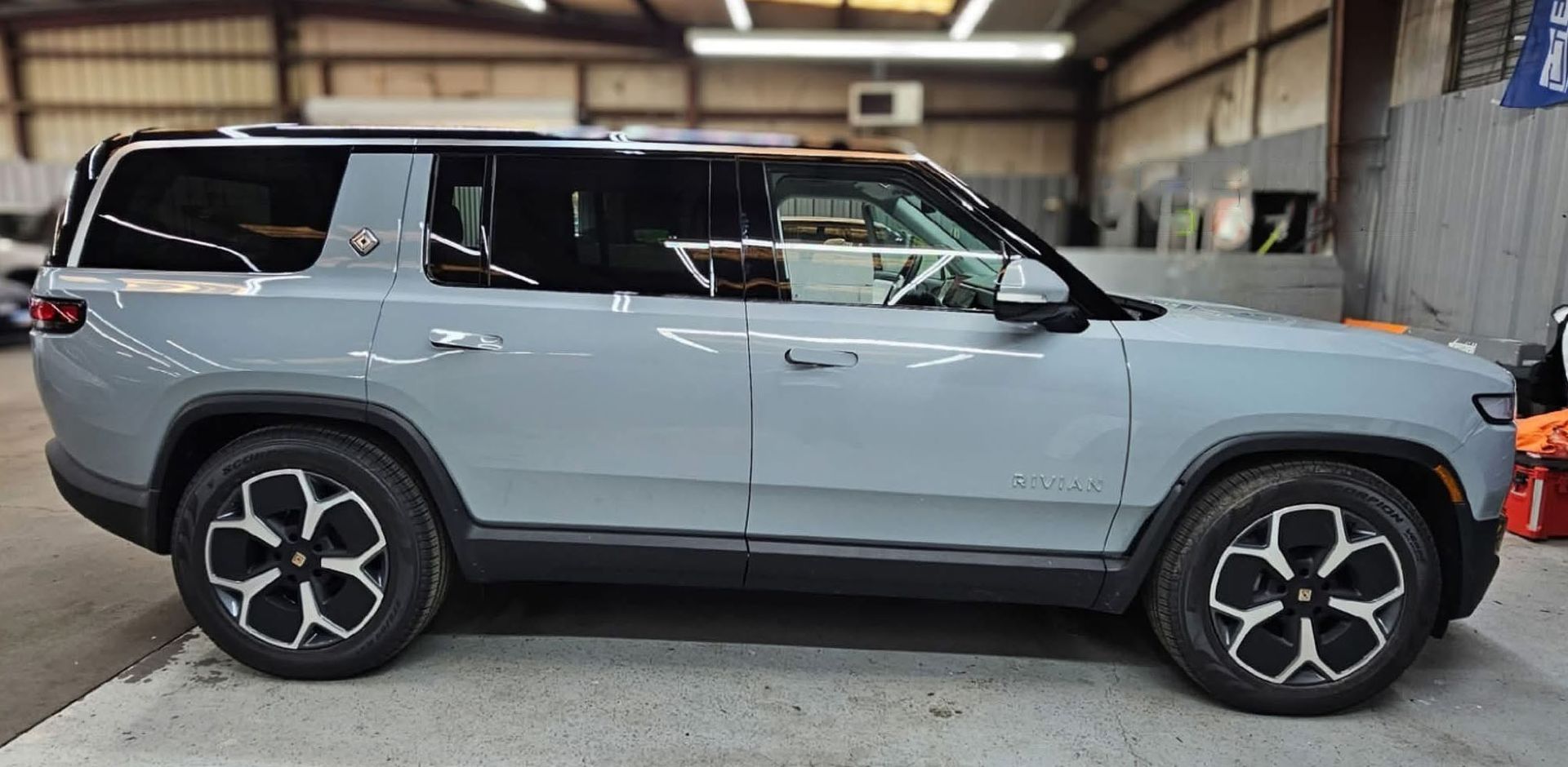 Light gray SUV parked indoors, side view with black wheels and roof rails