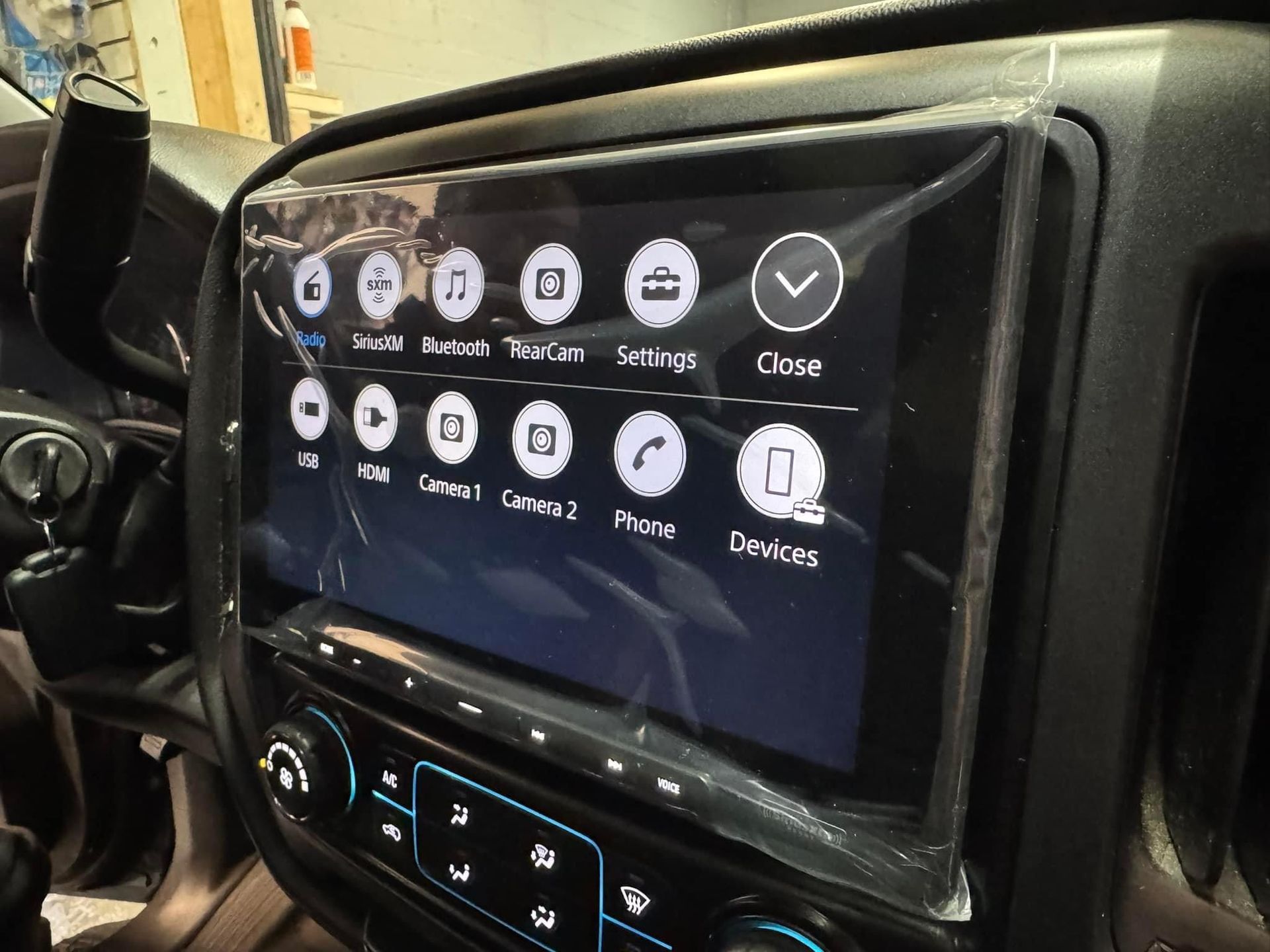 Car dashboard touchscreen showing app icons and controls on a black infotainment screen