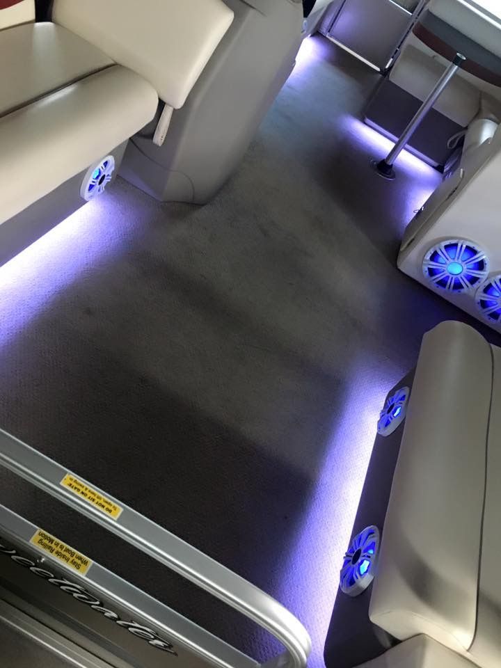 Interior of a bus or van with beige seats and purple floor lighting along the aisle.