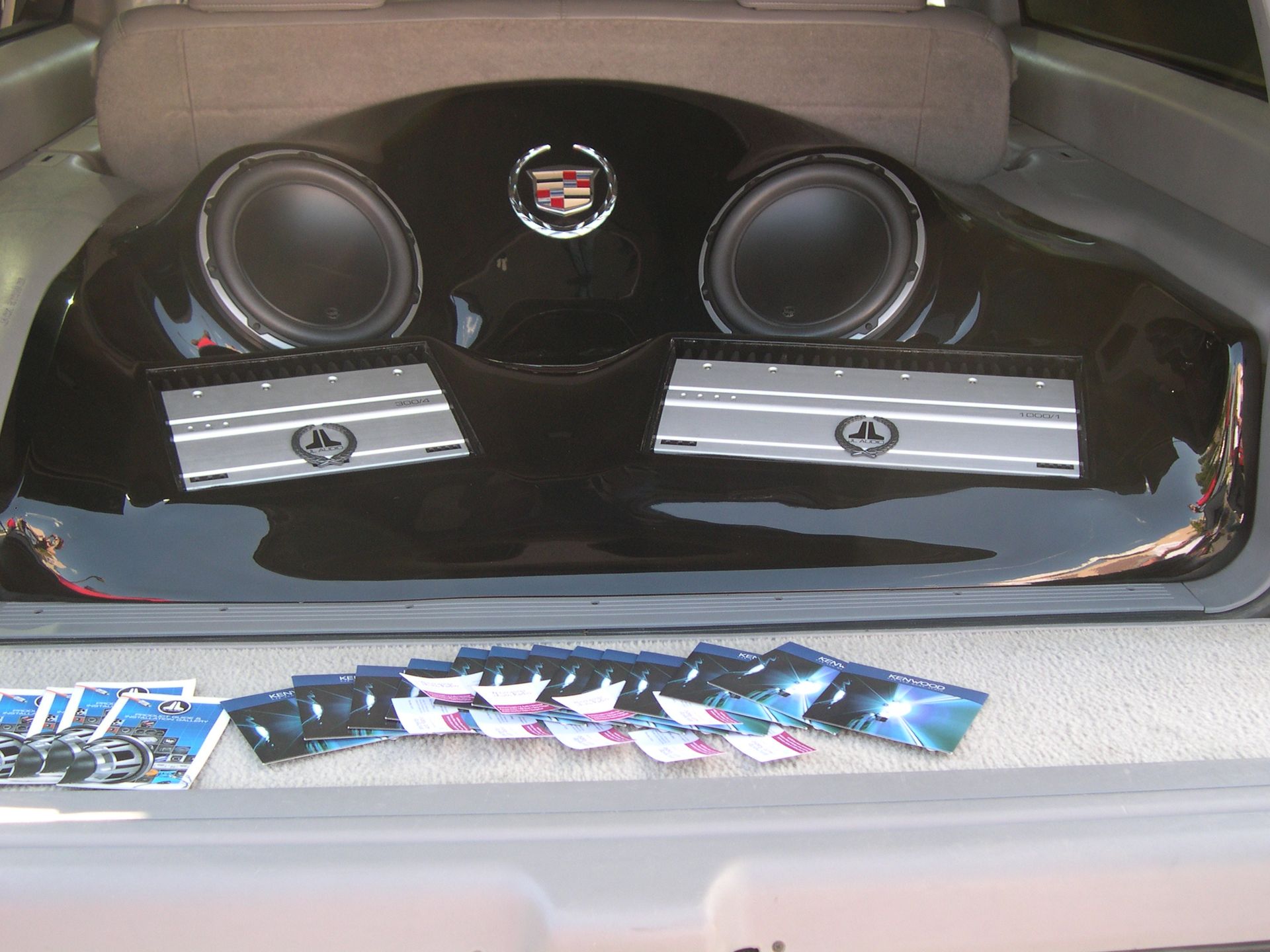 Custom car audio setup with two large speakers and silver amplifier boxes in a trunk