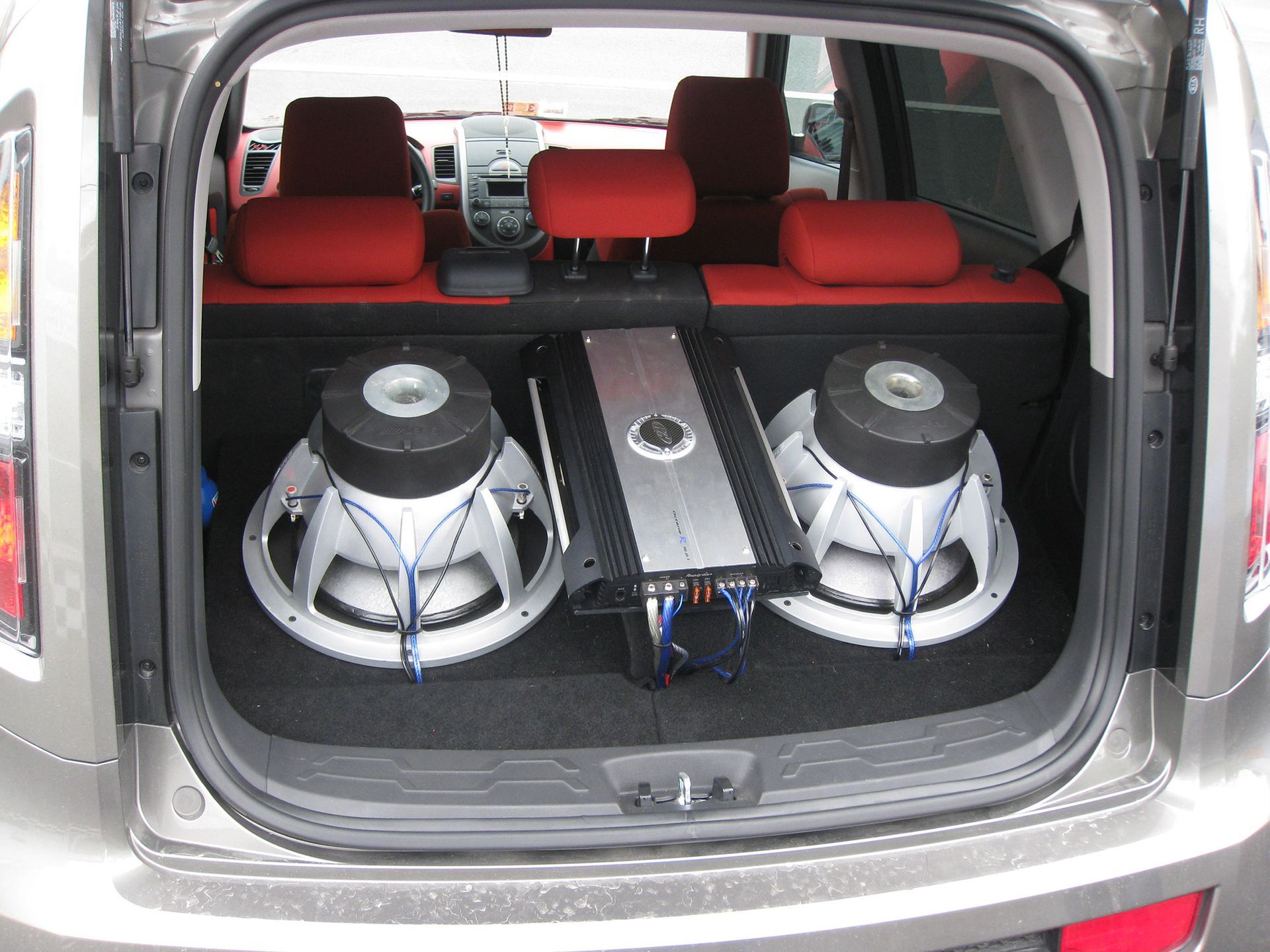 Car trunk with a custom subwoofer audio system and red seats visible inside