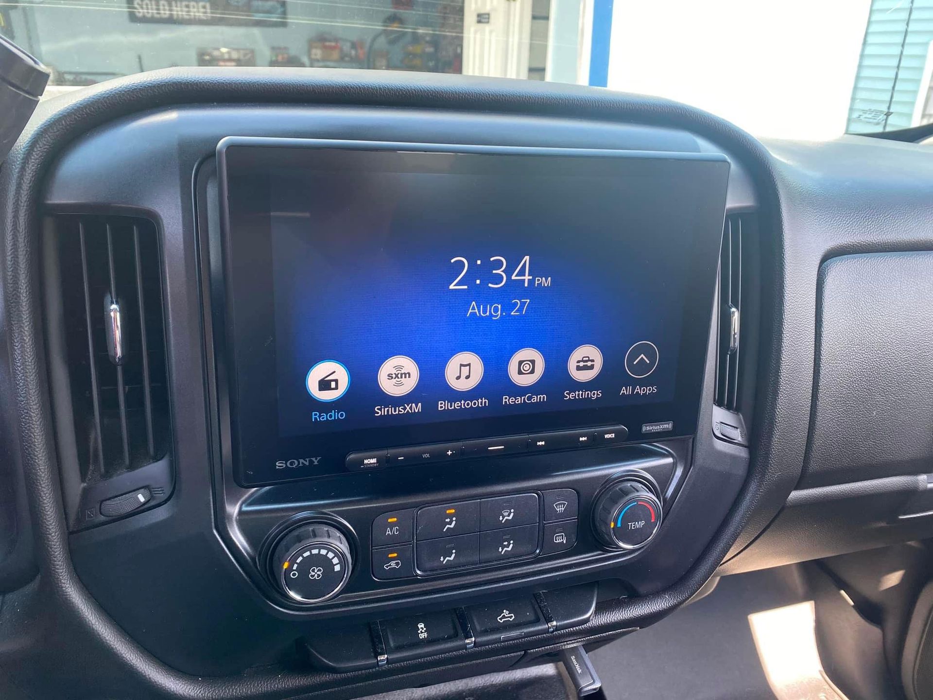 Car dashboard center console with touchscreen radio display and climate controls, showing 2:34.