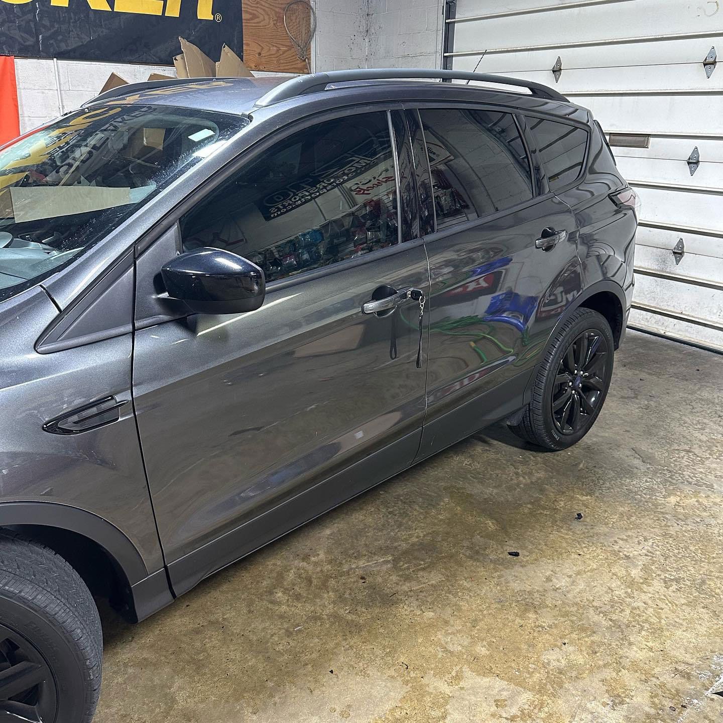 Dark gray SUV parked in a garage, side view with tinted windows and black wheels
