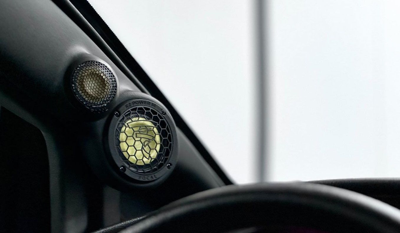Close-up of two round dashboard lights beside a car windshield, one glowing amber