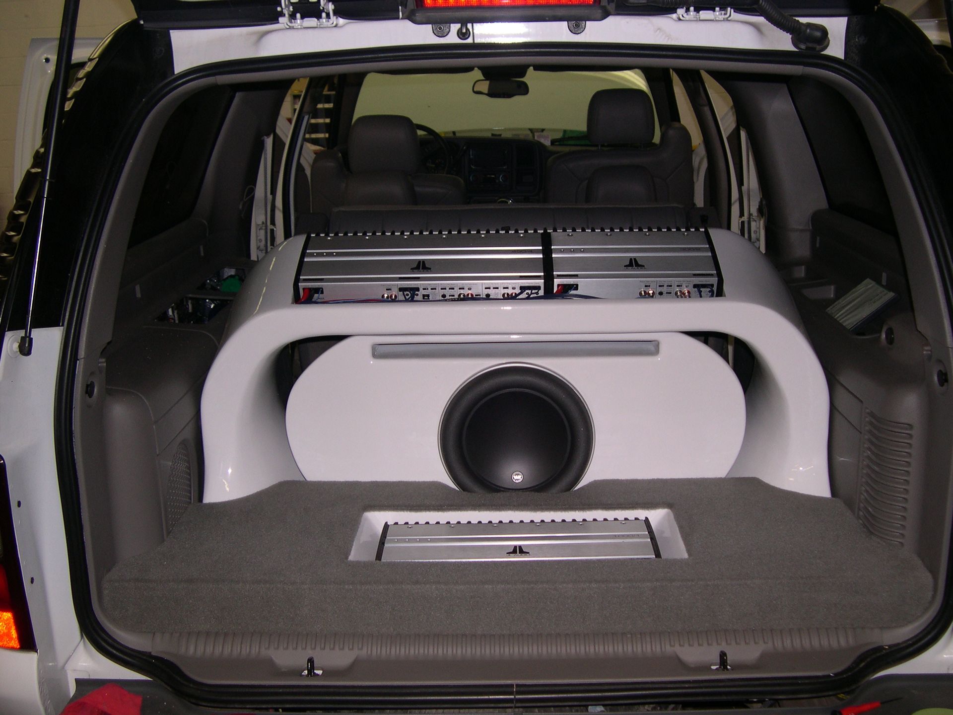 SUV cargo area with custom white subwoofer enclosure and speakers in the trunk