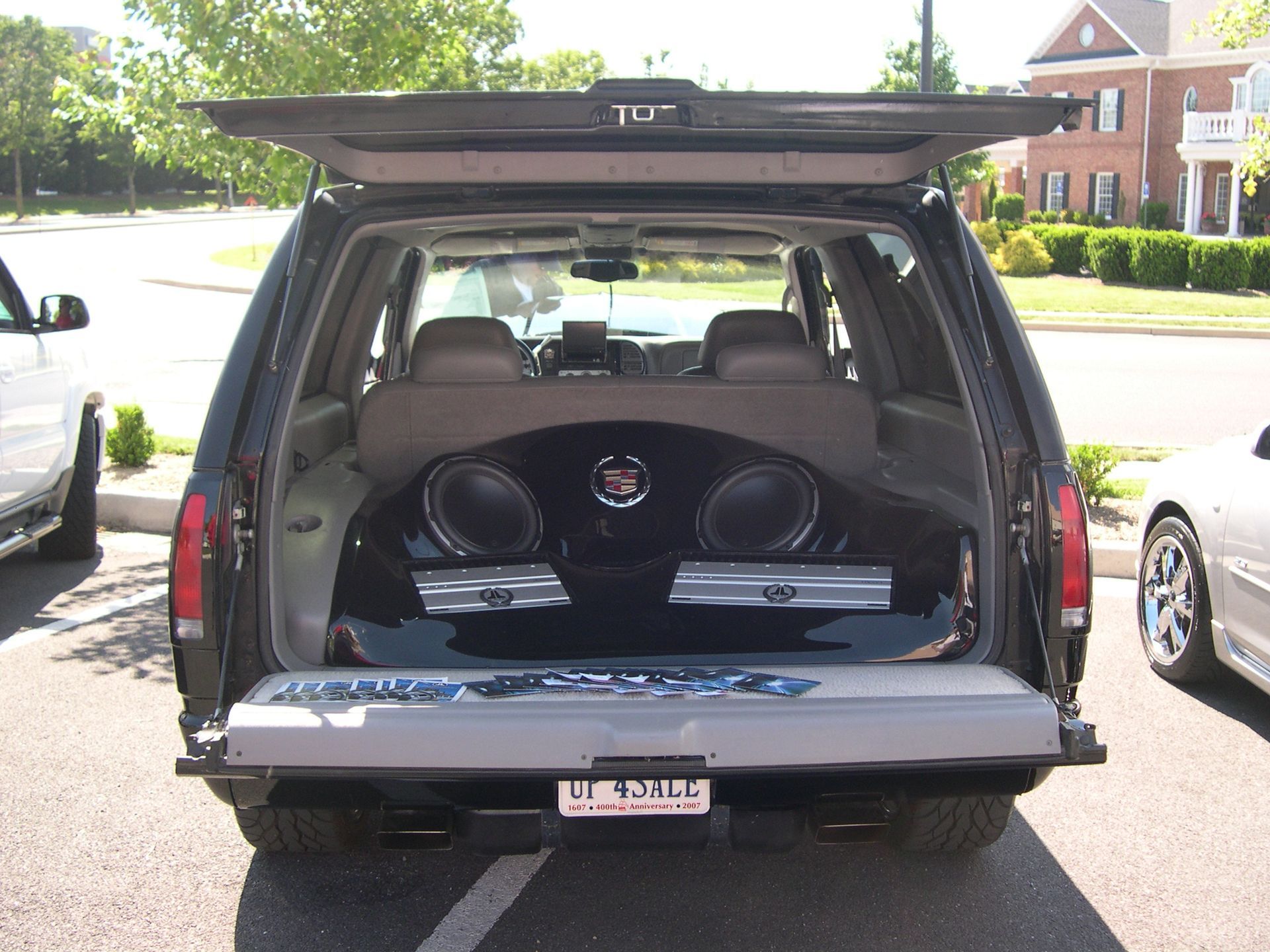 Open SUV hatch with custom speaker enclosure in the cargo area at a residential driveway