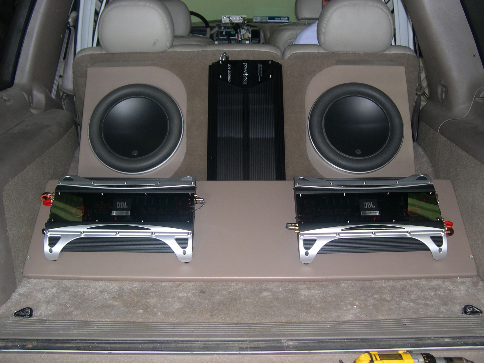 Car trunk with a custom speaker and subwoofer audio setup in beige and black.
