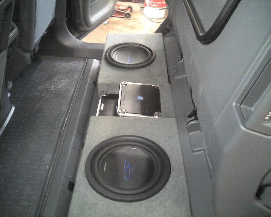 Car interior with custom subwoofer speakers and a phone on a gray center console.