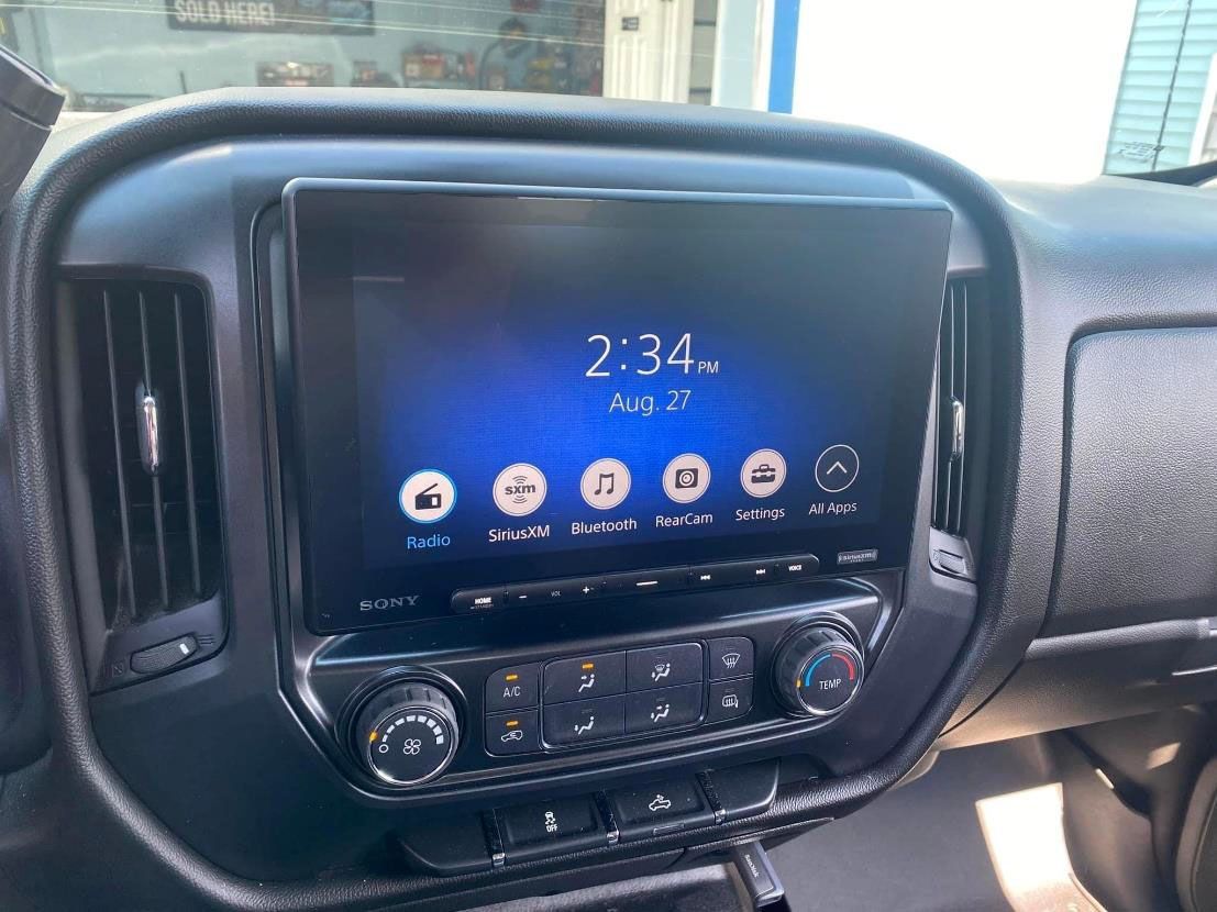 Car dashboard with a touchscreen infotainment system showing the time and app icons.