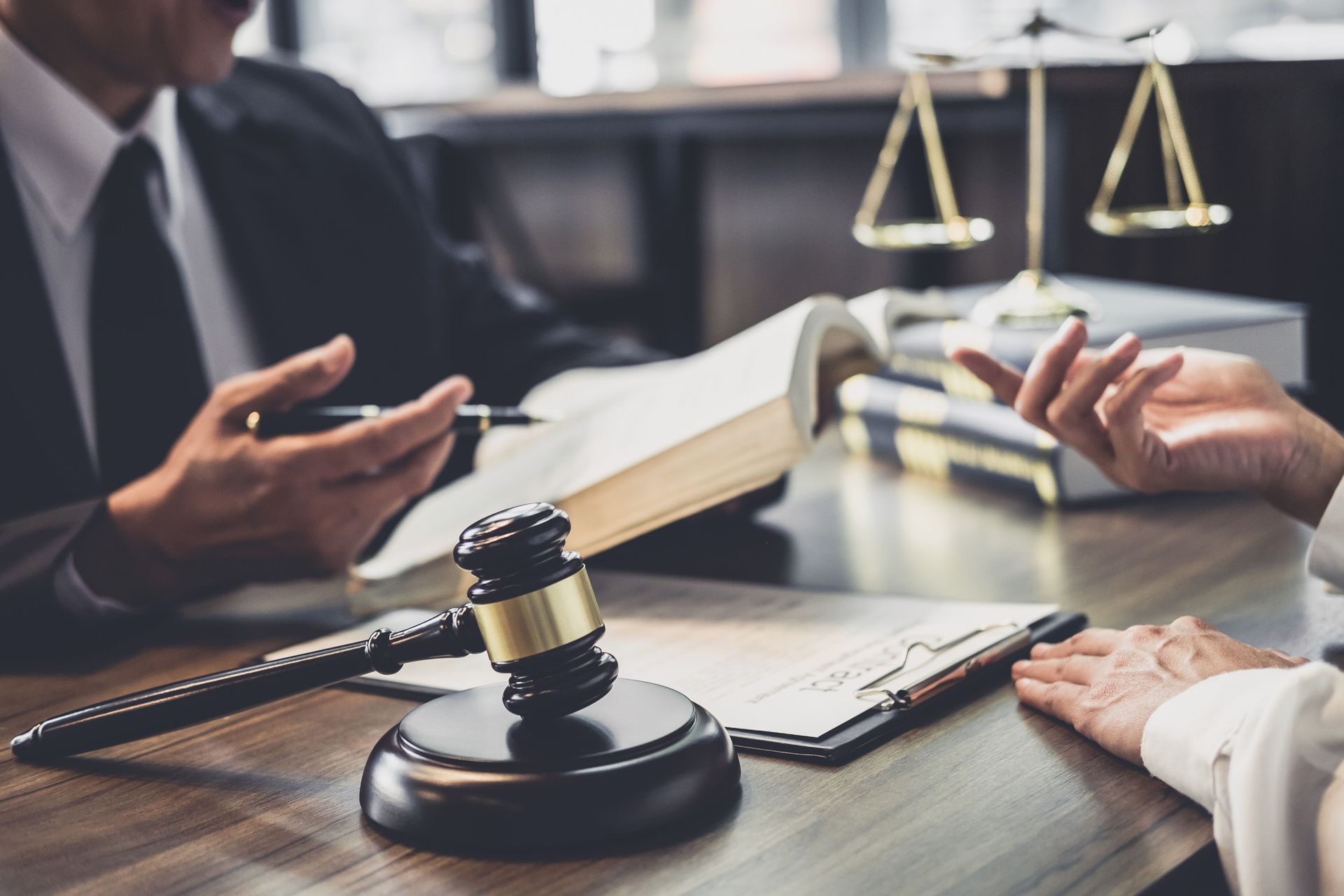 Lawyer discussing a case at a desk with a gavel, open book, and justice scales
