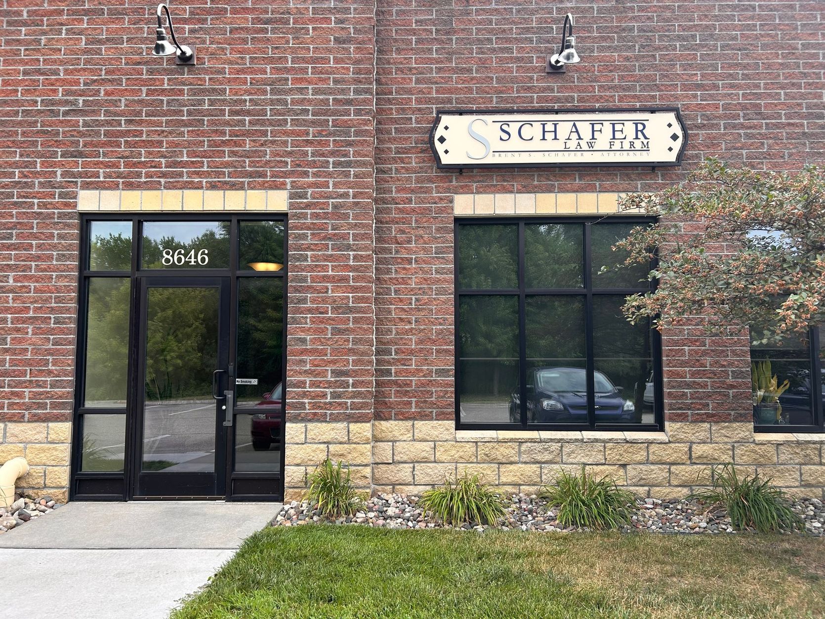 Brick storefront with sign reading “SCHAFER” above dark windows and a glass door.