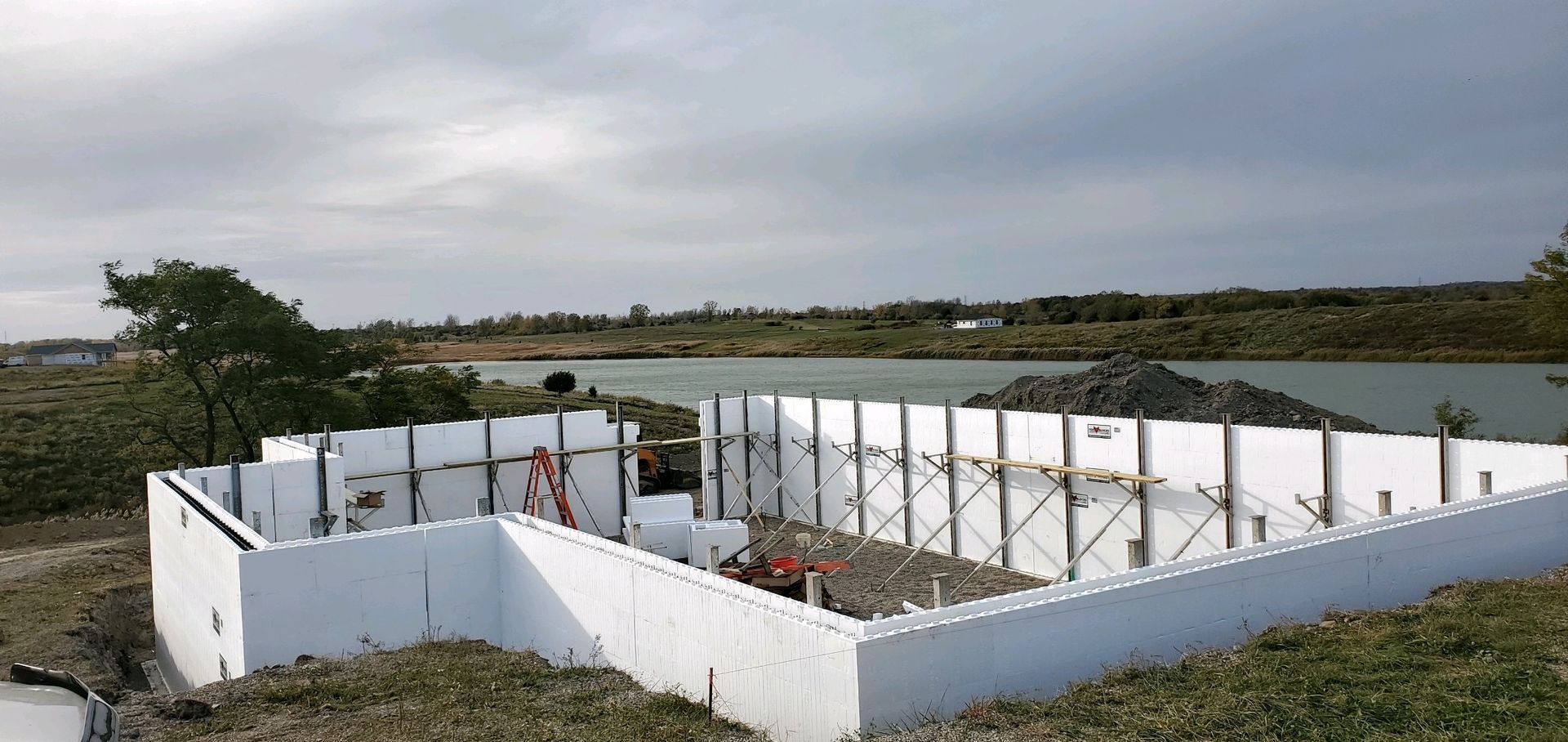 A house is being built in a field with a lake in the background.