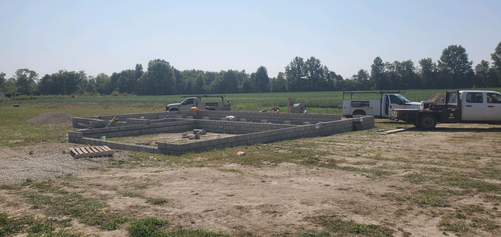 A white truck is parked in a dirt field next to a pile of bricks.