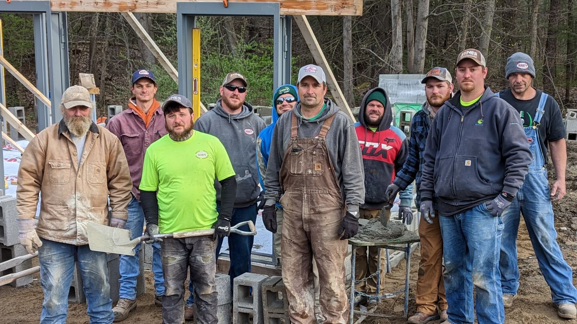 A group of construction workers are posing for a picture on a construction site.