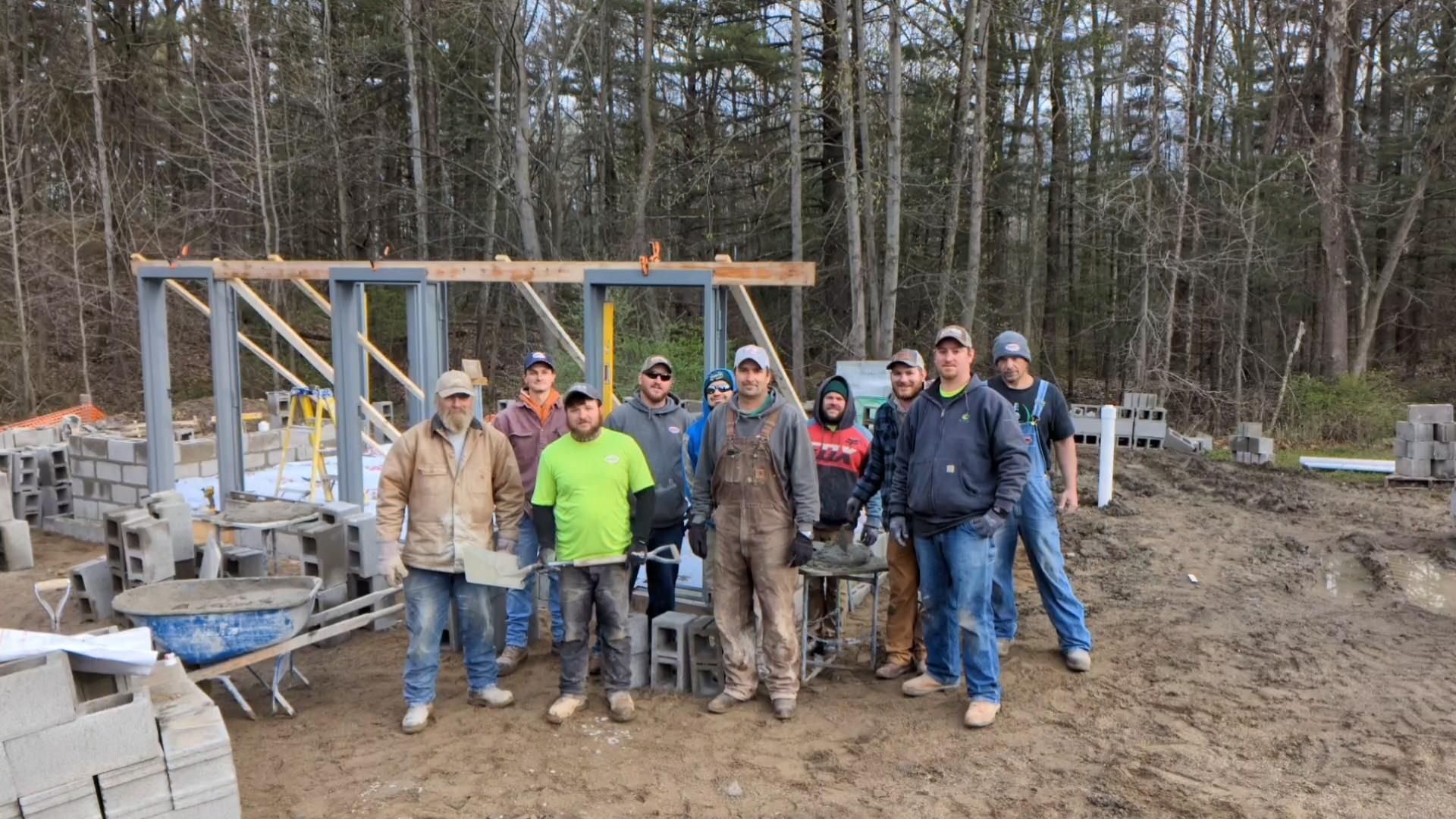 A group of construction workers are posing for a picture on a construction site.
