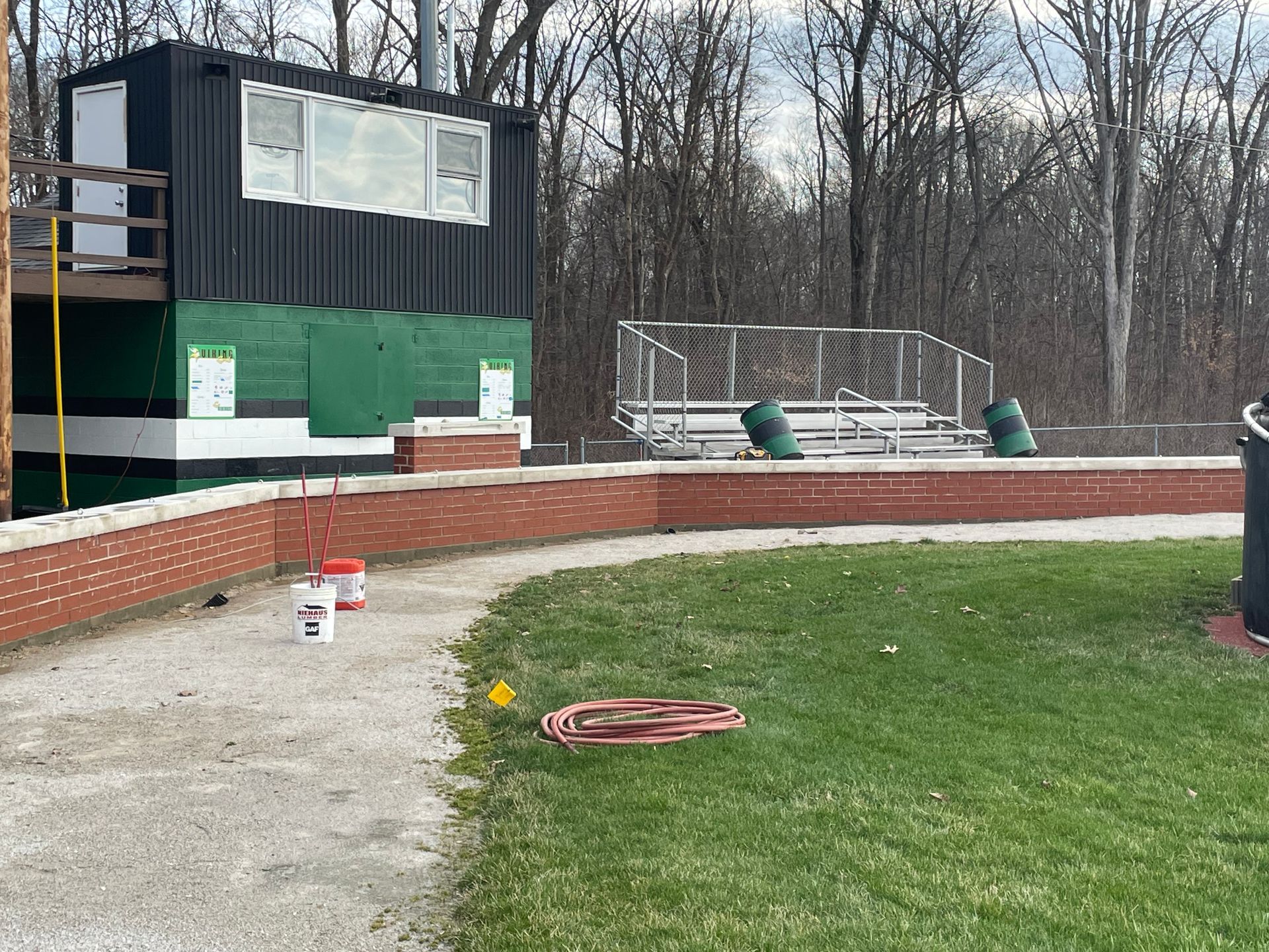 A baseball field with a brick wall and a bleacher in the background.