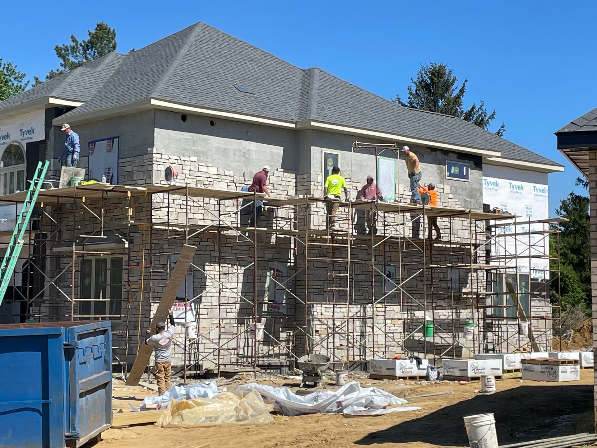 A group of construction workers are working on the side of a house.