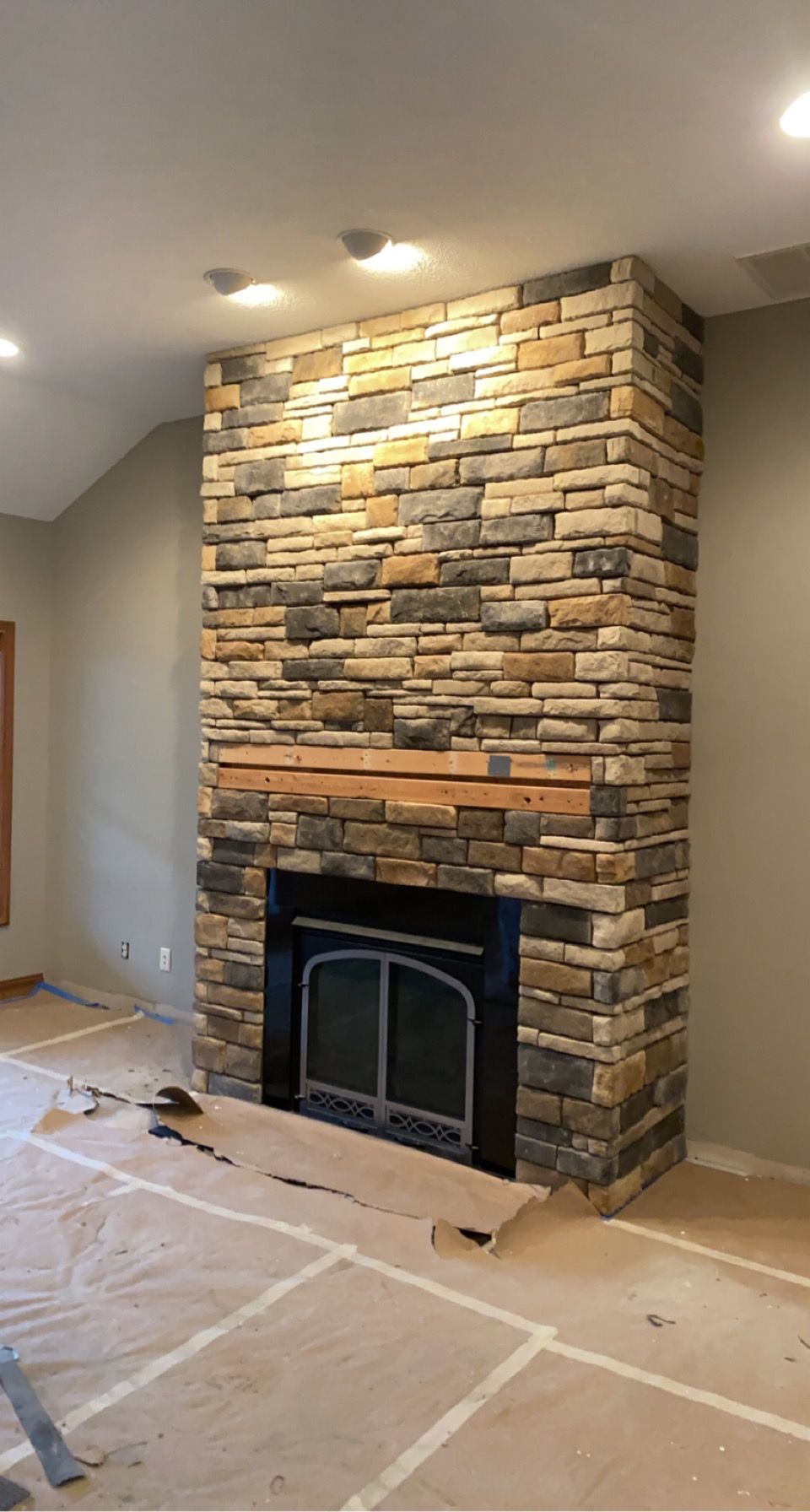 A living room with a large stone fireplace in the middle of it.