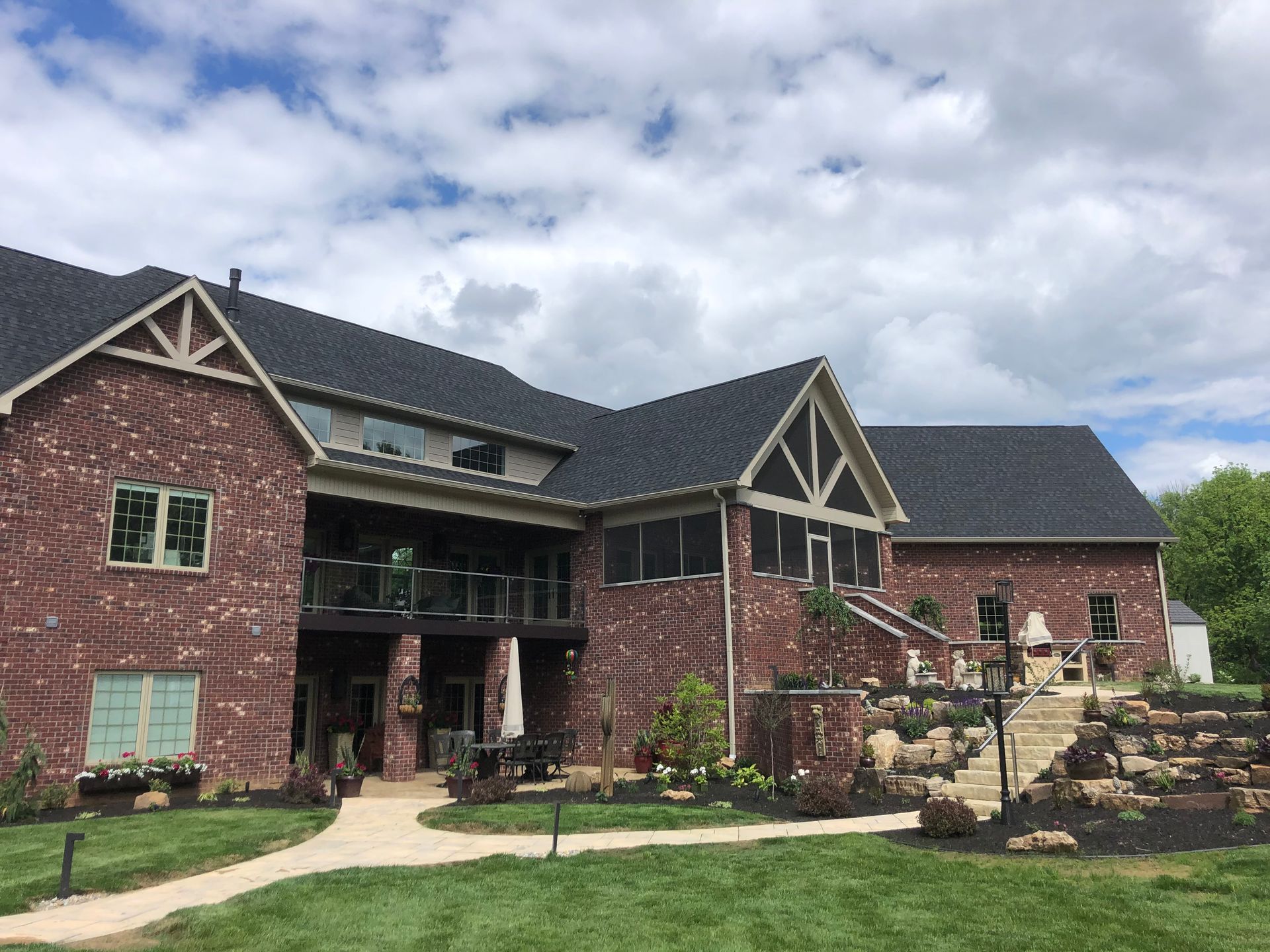 A large brick house with a black roof and a walkway leading to it.