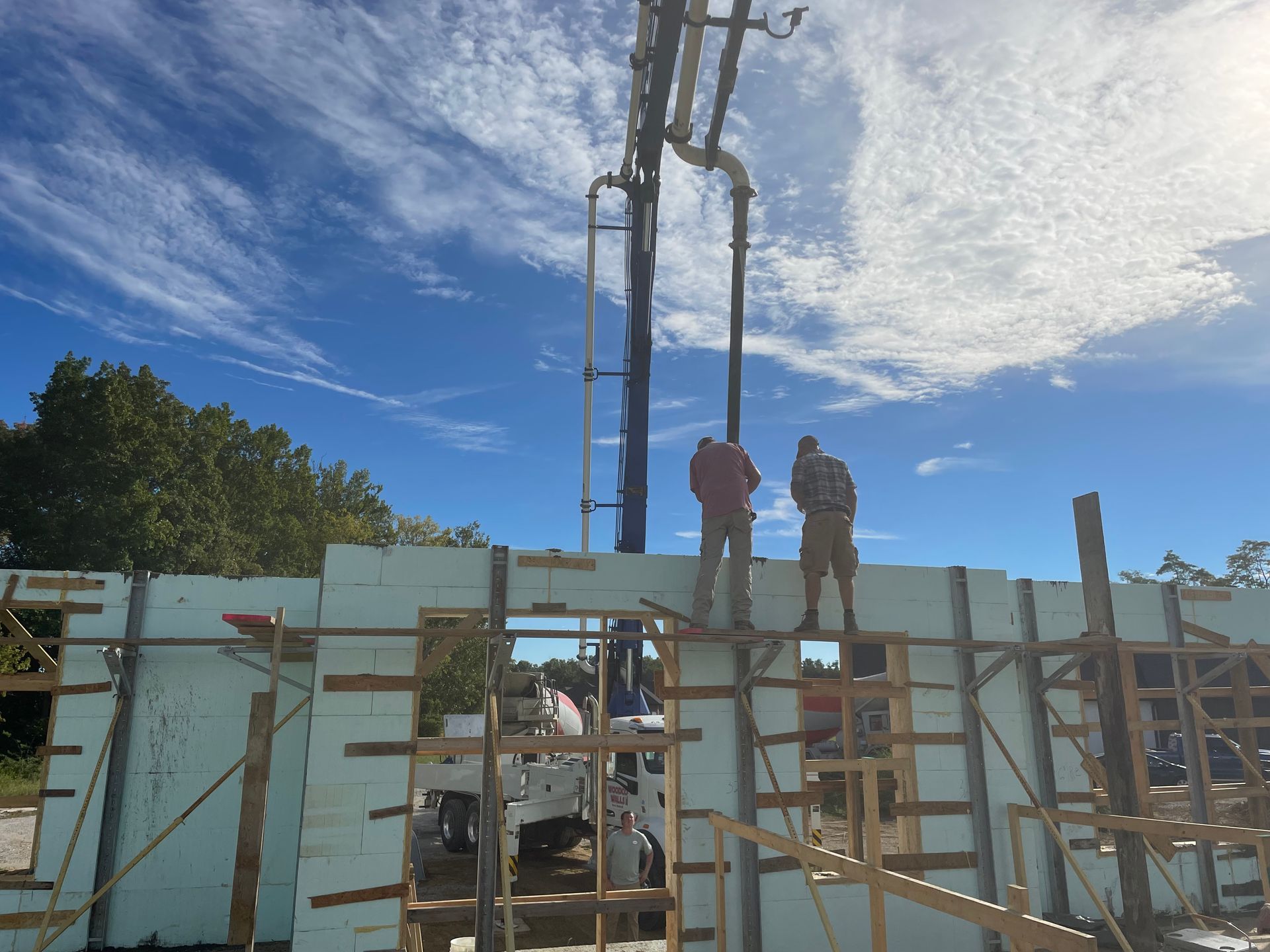 A couple of men are standing on top of a building under construction.