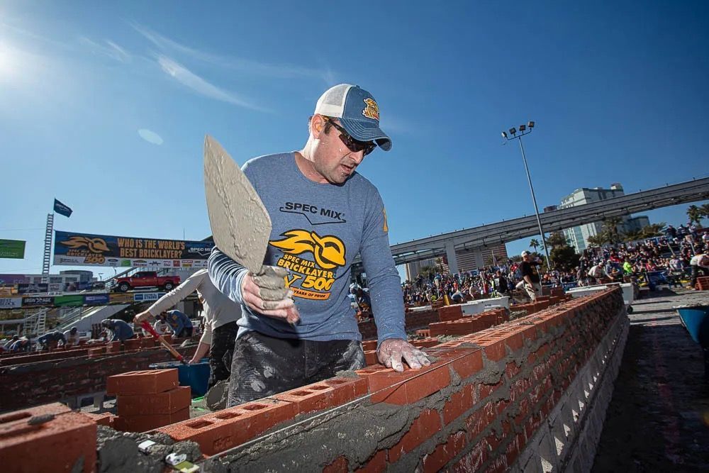 A man is building a brick wall with a trowel.