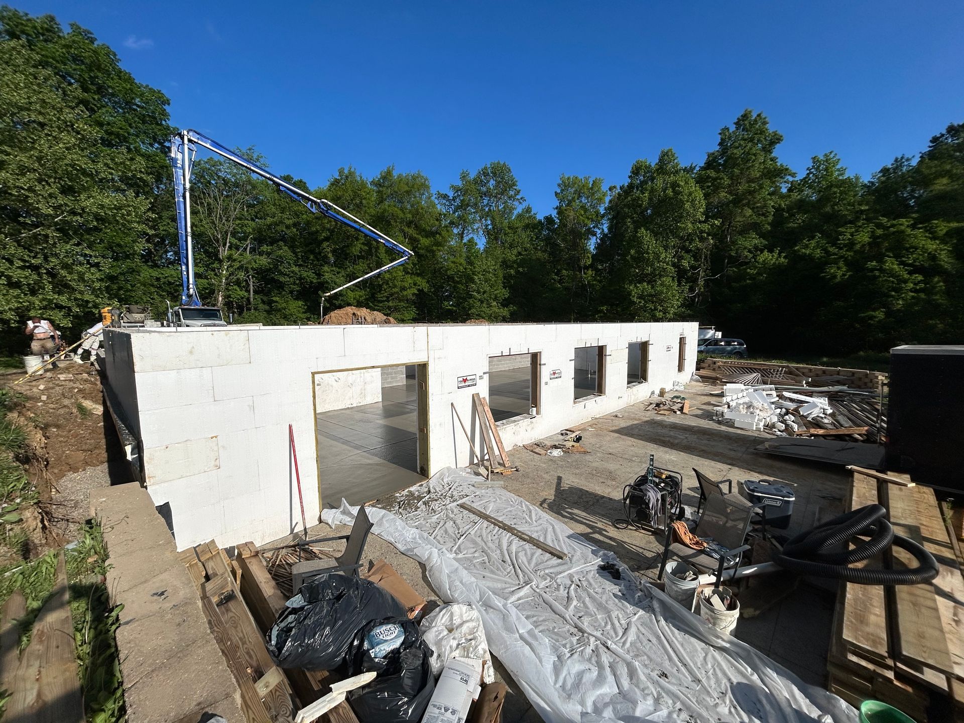A large white building is being built in the middle of a forest.