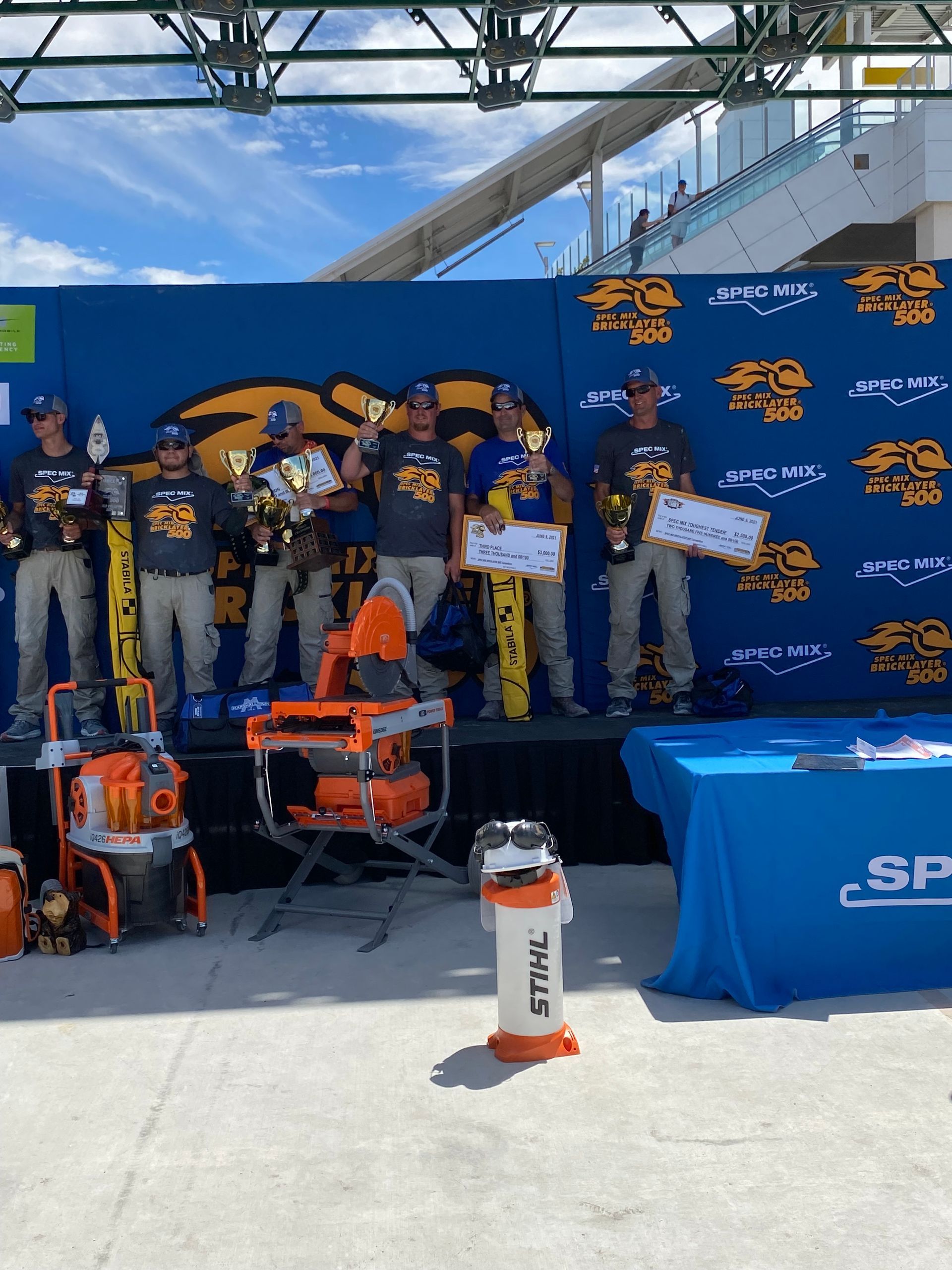 A group of men are standing on a stage holding trophies.
