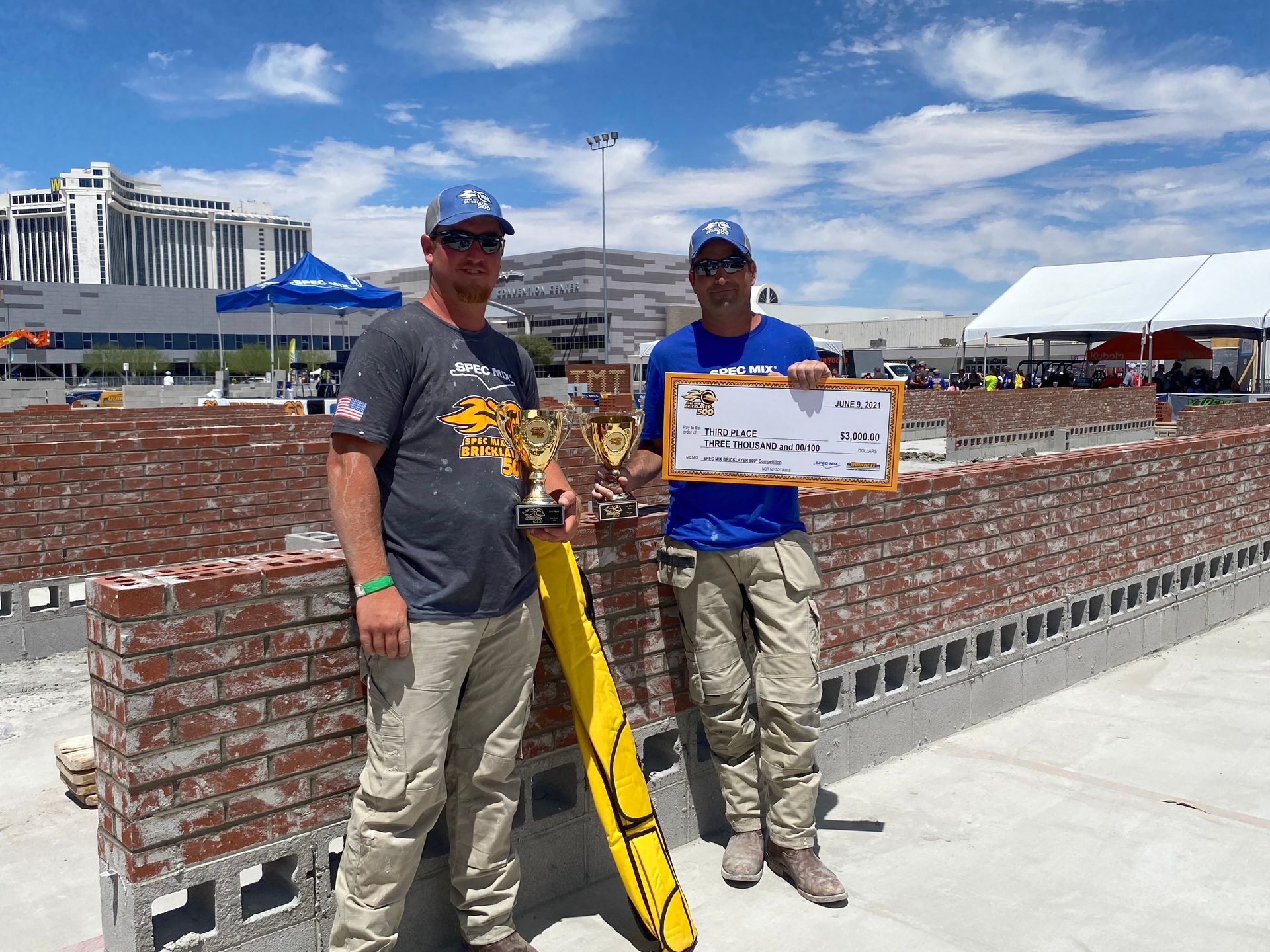 Two men are standing next to each other holding a check.