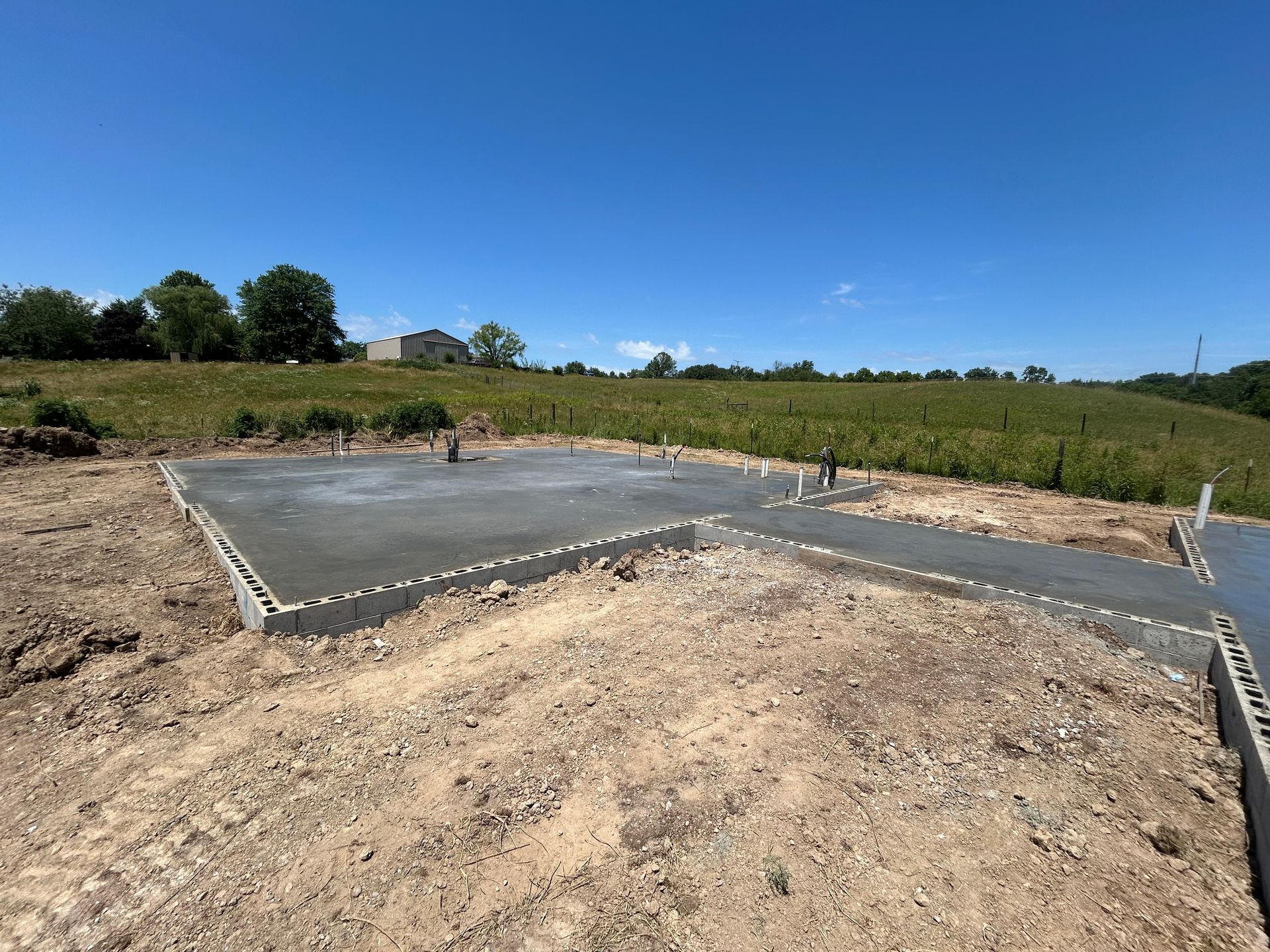 A concrete foundation is being built in a dirt field.
