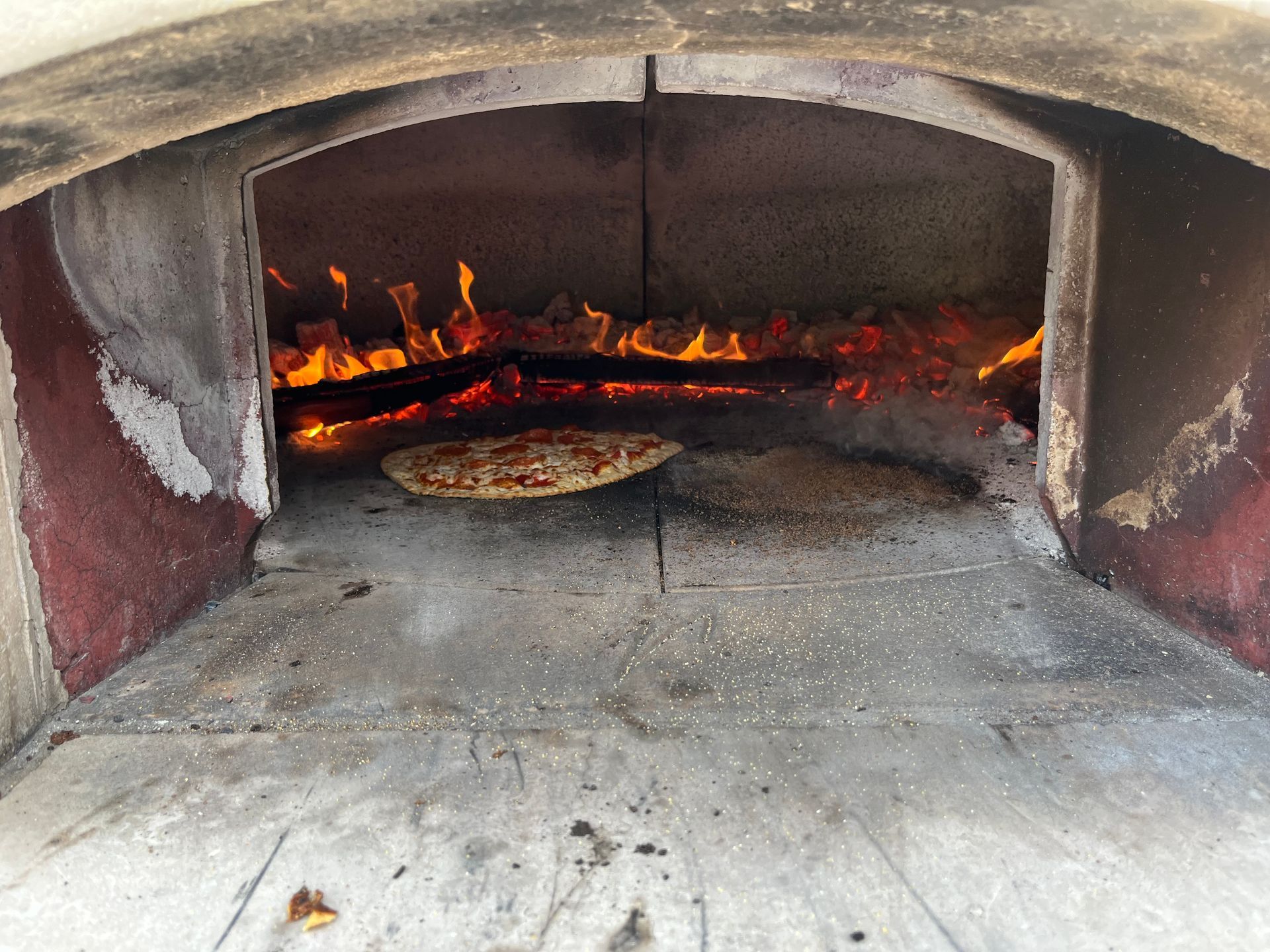 A pizza is being cooked in a brick oven