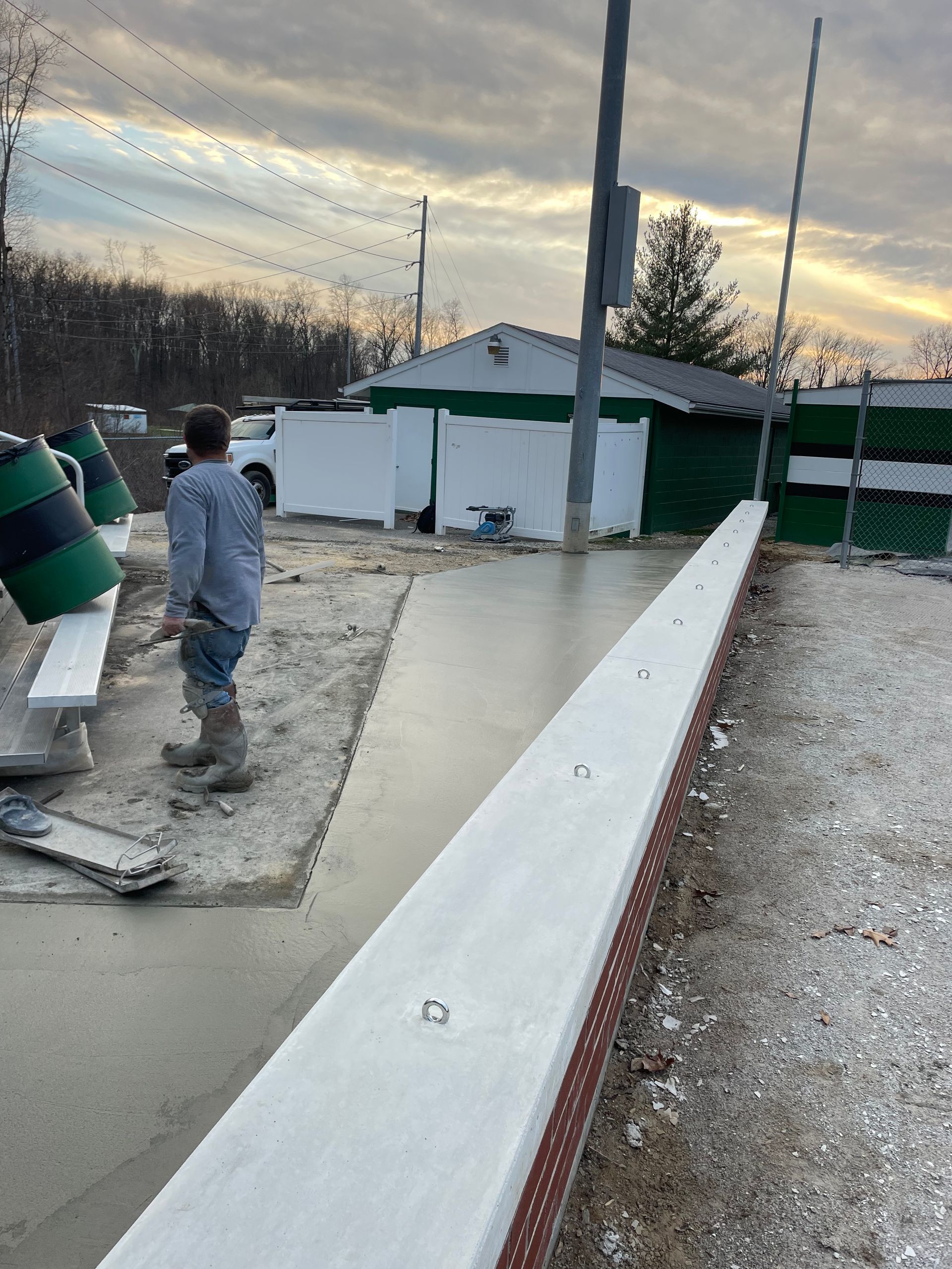 A man is standing next to a white railing on a sidewalk.
