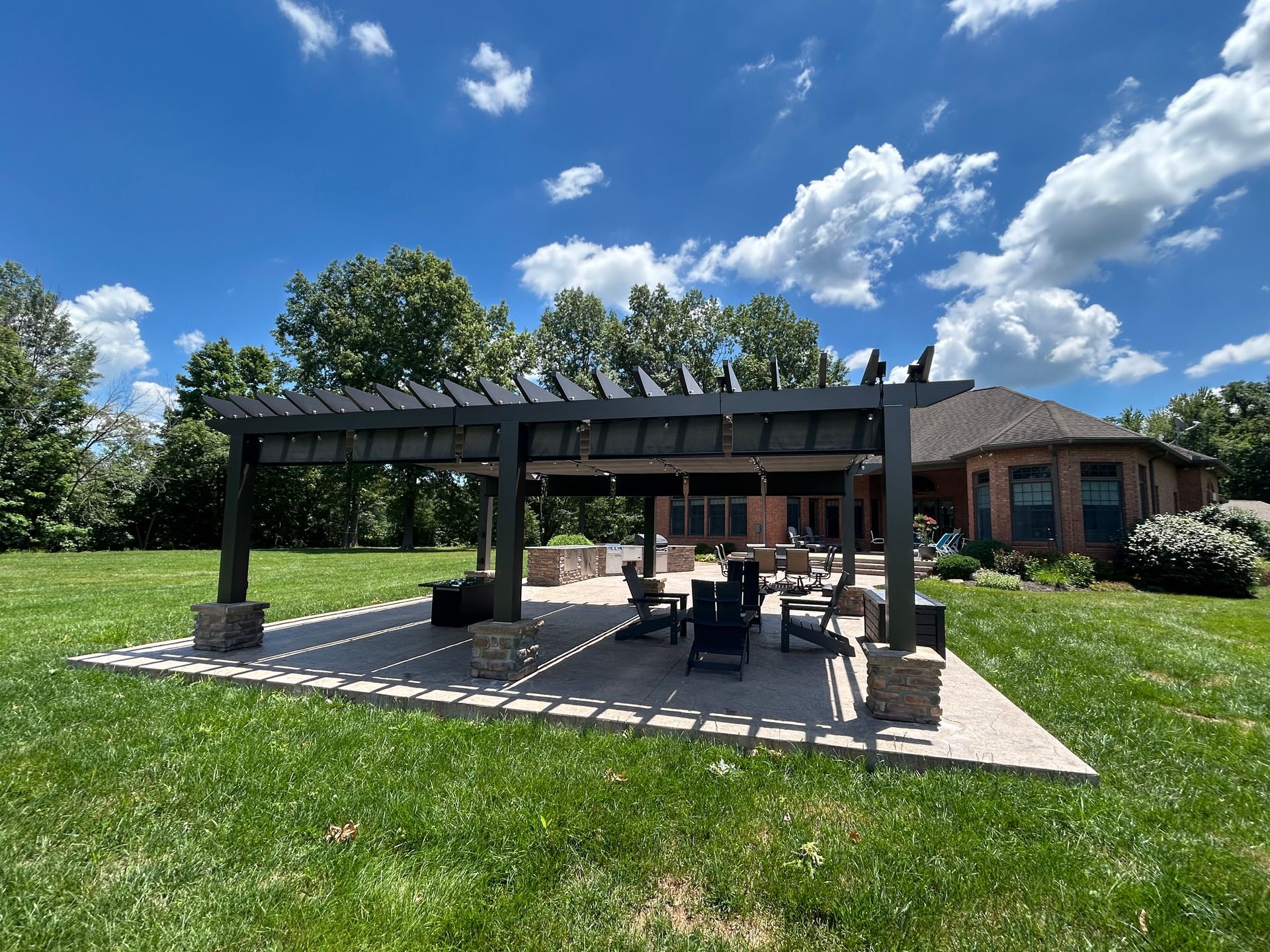 There is a pergola in the middle of a lush green field.
