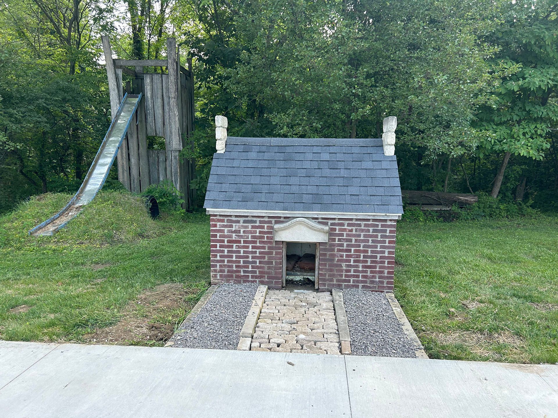 A small brick house with a slide in the background.