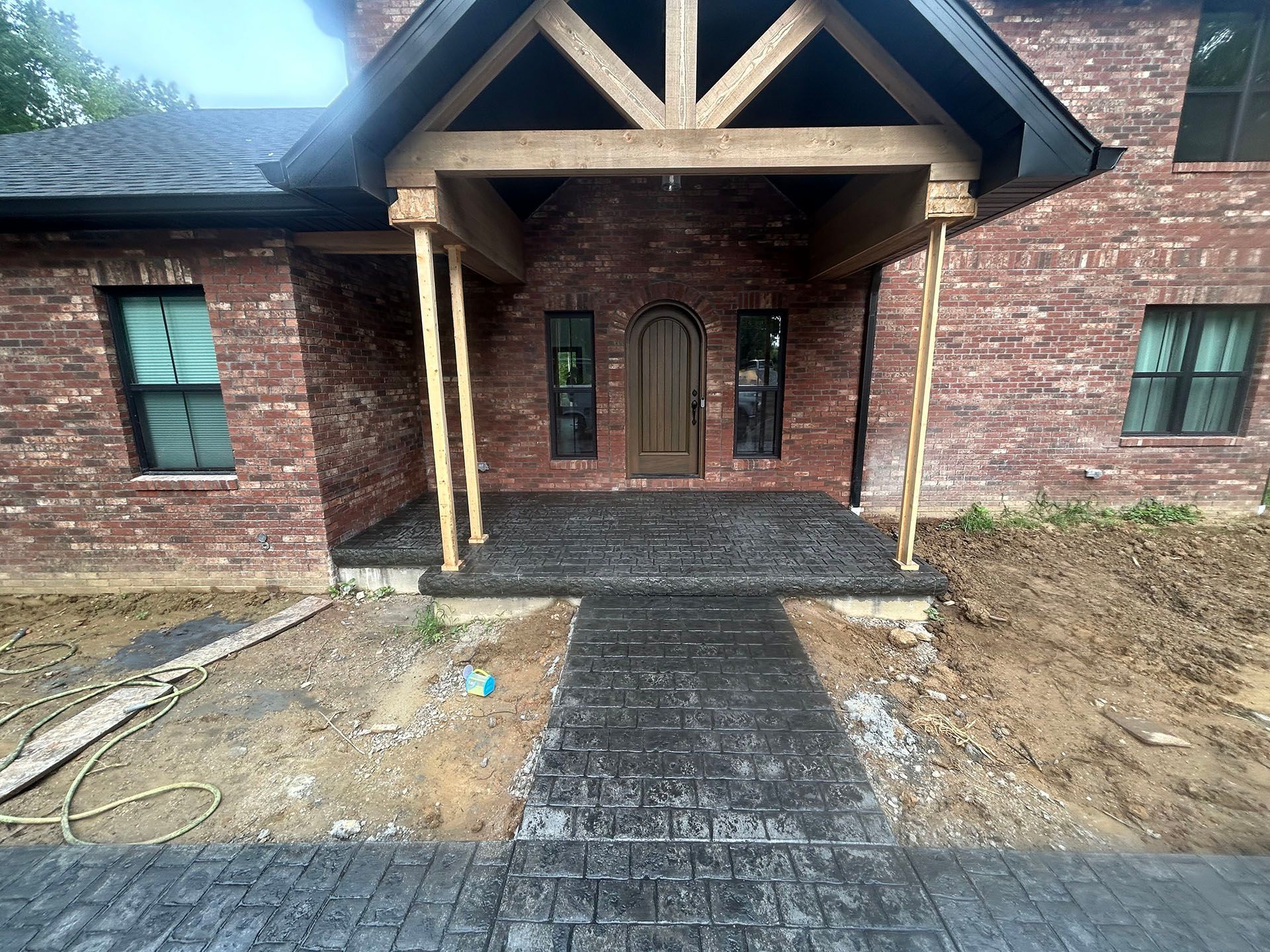 A brick house with a porch and a concrete walkway leading to it.
