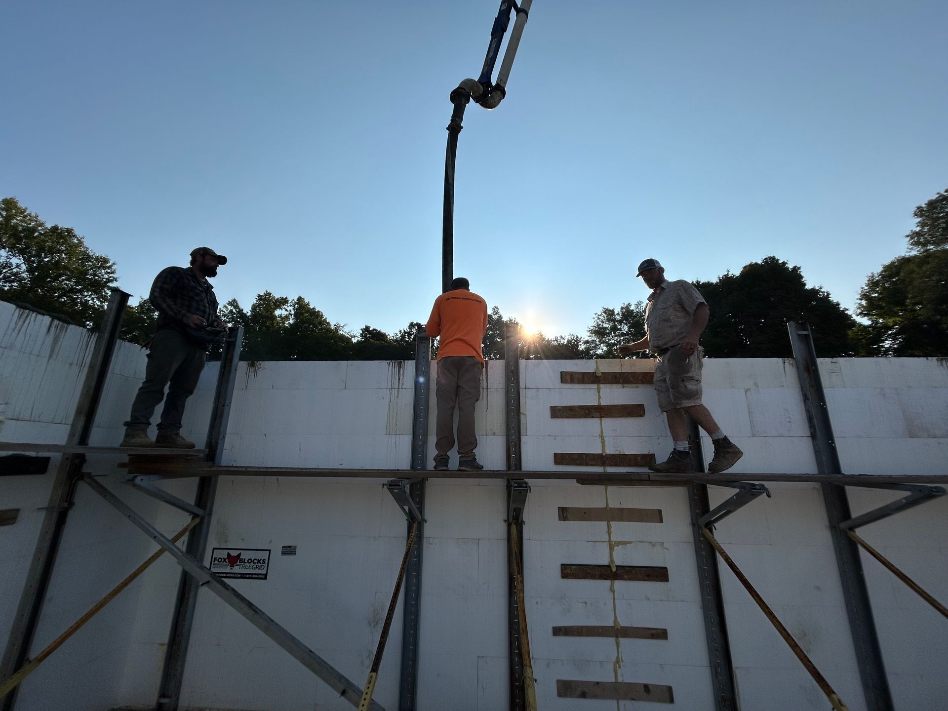 A concrete pump is being used to pour concrete into a wall