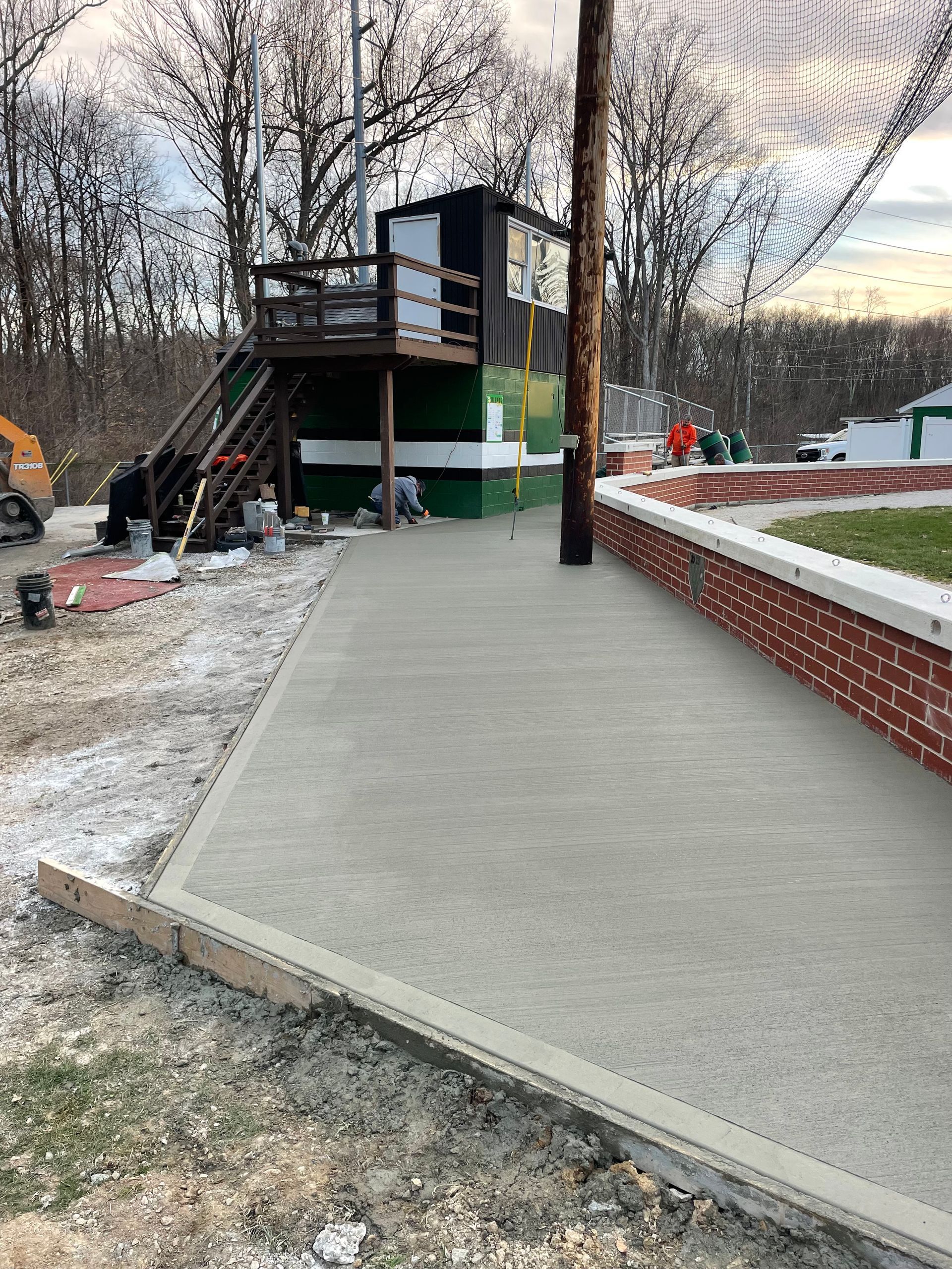 A concrete walkway is being built next to a brick wall.