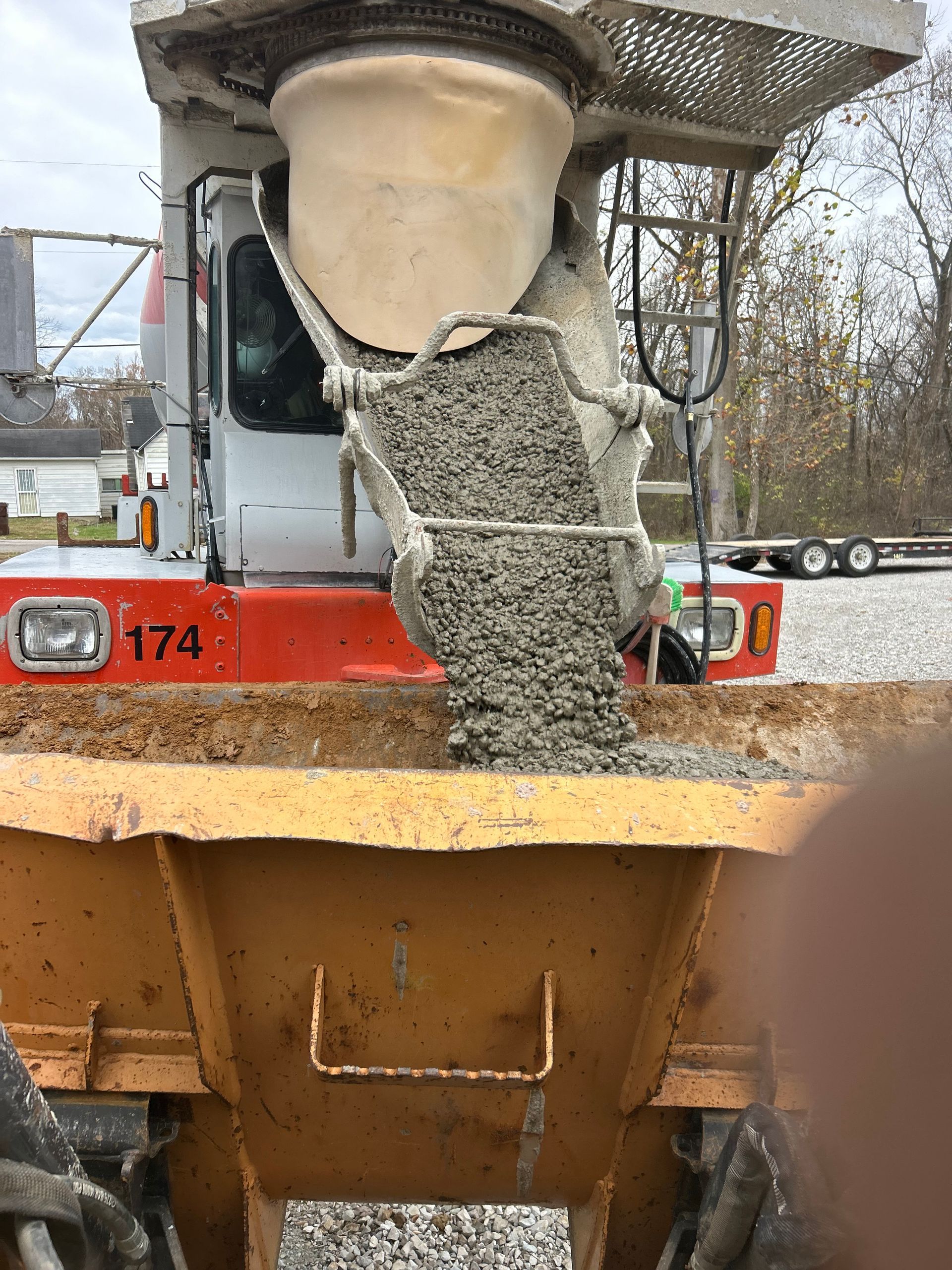 A truck is pouring concrete into a dumpster.