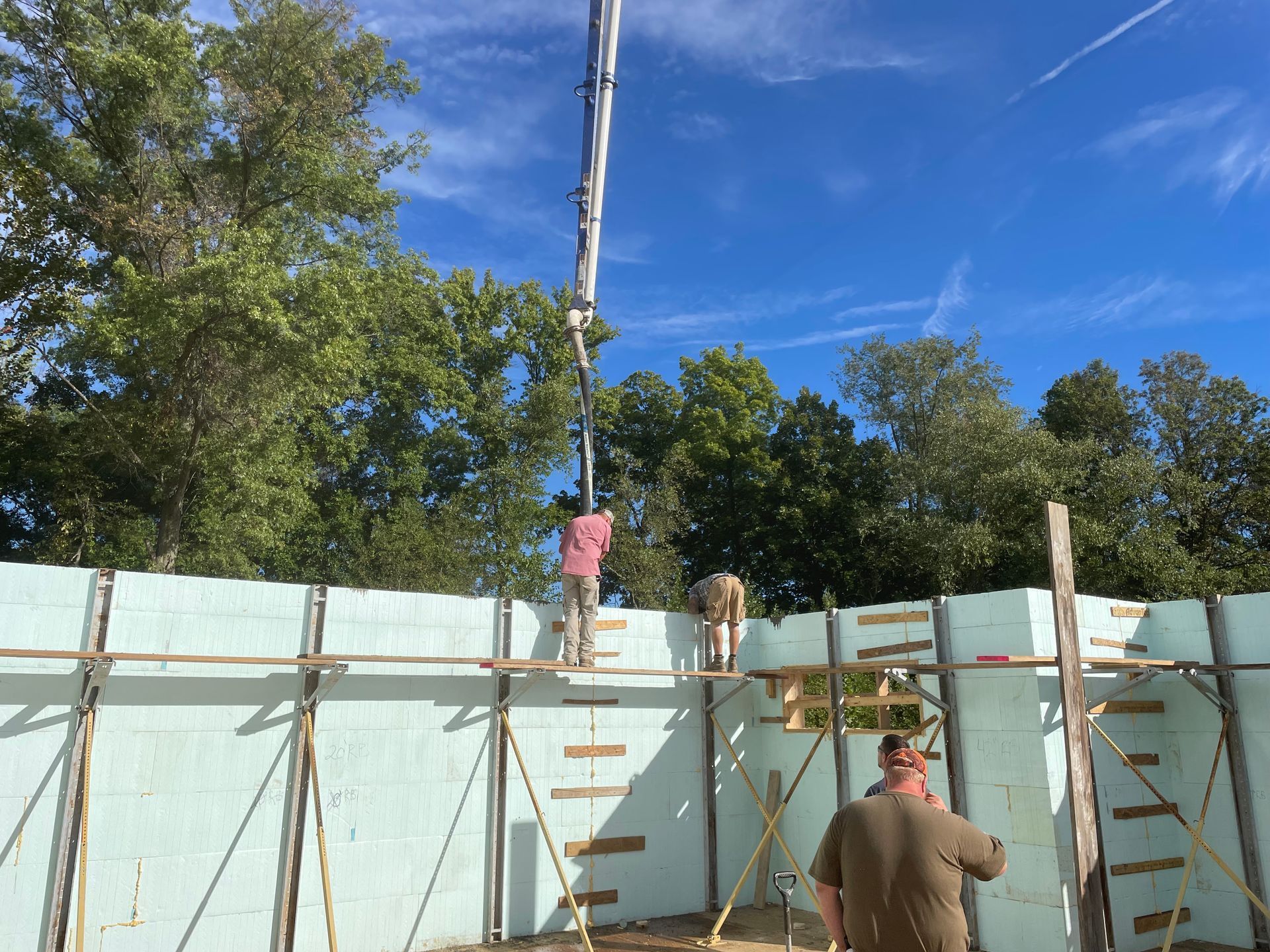 A concrete pump is being used to pour concrete into a wall